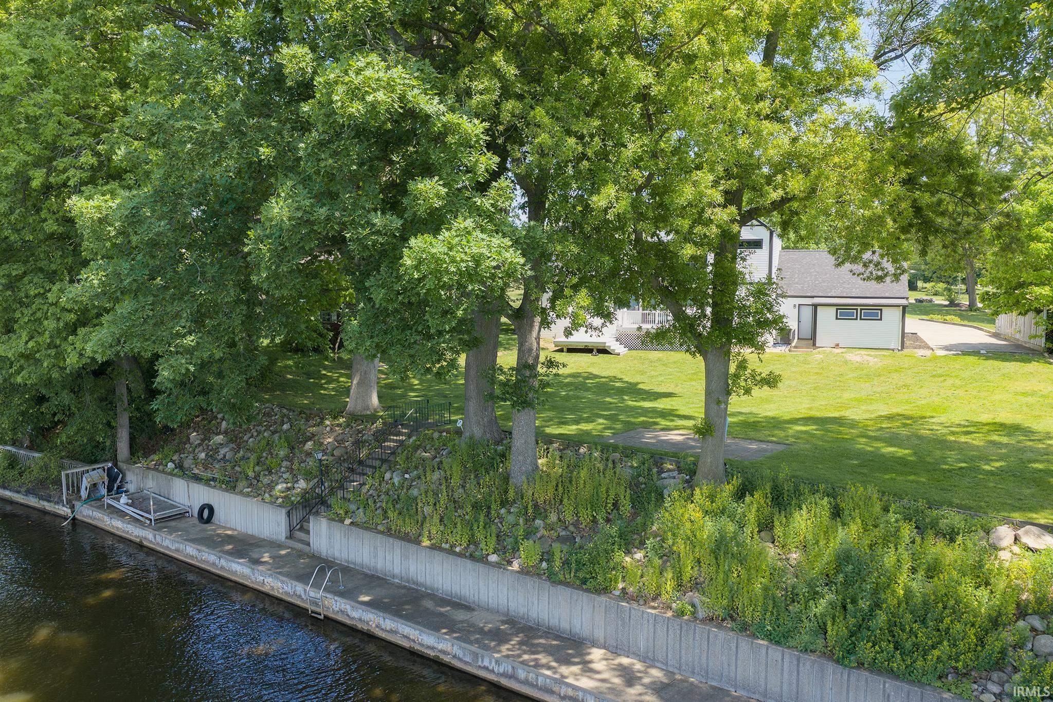 Waterfront property featuring a concrete seawall with integrated ladders, a boat lift, and a private dock