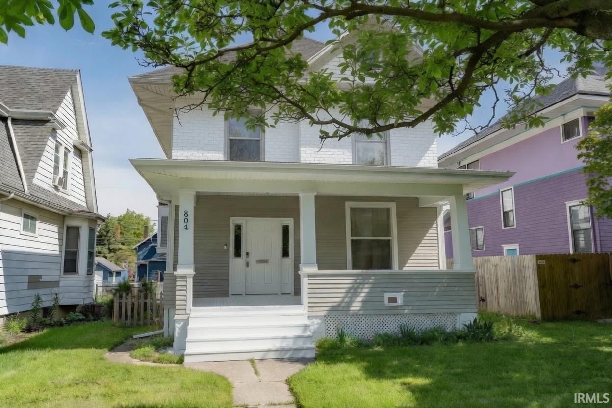 Two-story property featuring a covered front porch with white columns, a white double entry door, and white painted steps