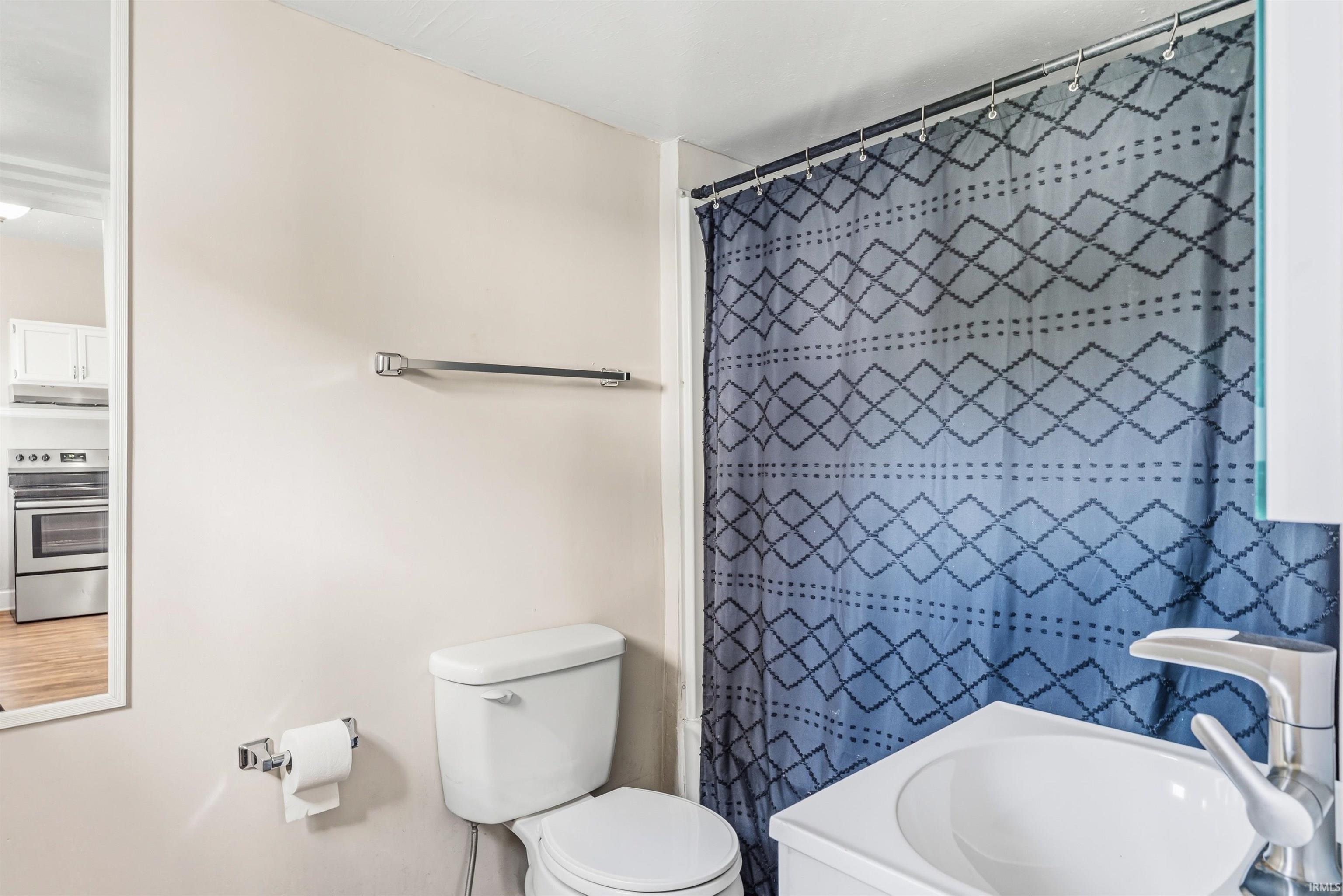 Bathroom featuring a white toilet, wall-mounted towel bar, and a single vanity with a white vessel sink and modern chrome faucet