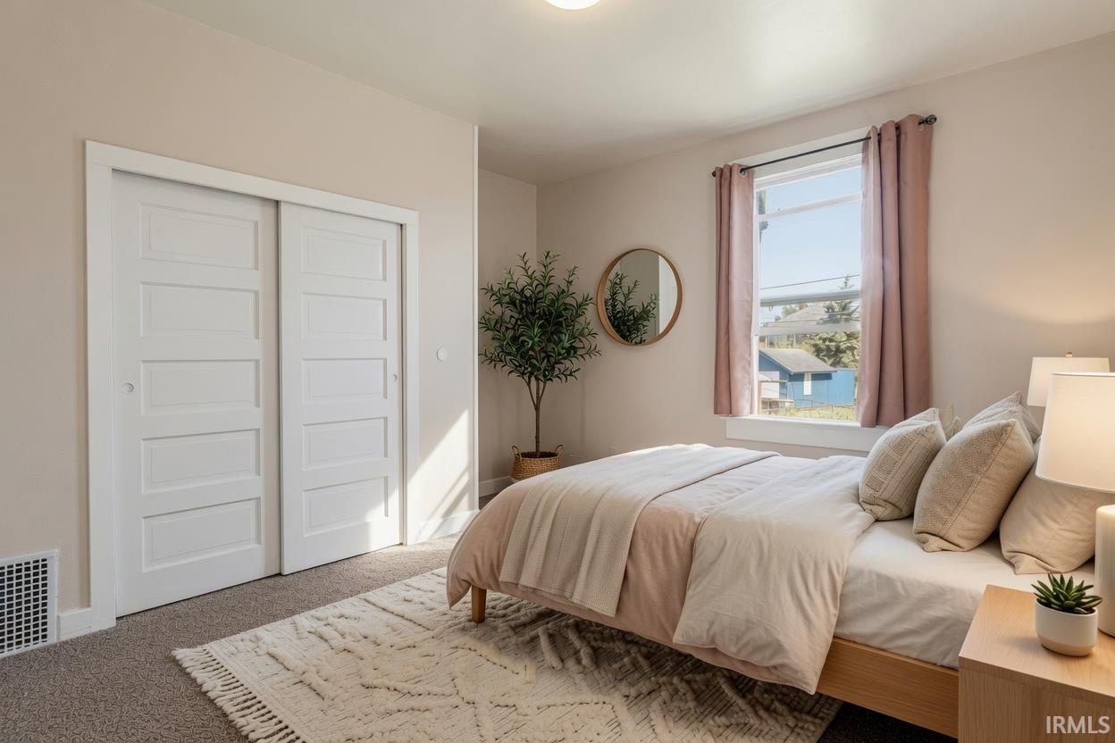 Spacious room featuring neutral-toned walls, a window with natural light, and plush carpeting