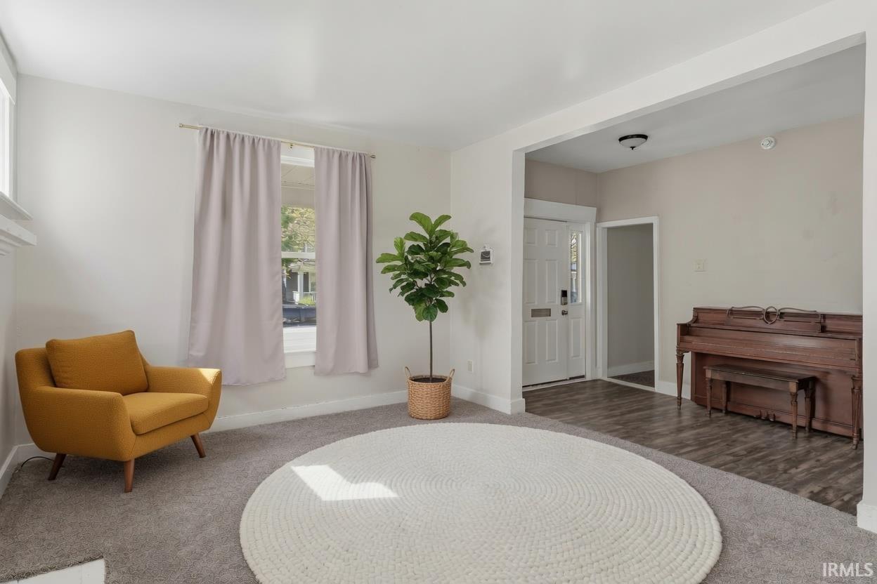 Bright living space featuring neutral-toned walls, windows with natural light, and a white front door with sidelight