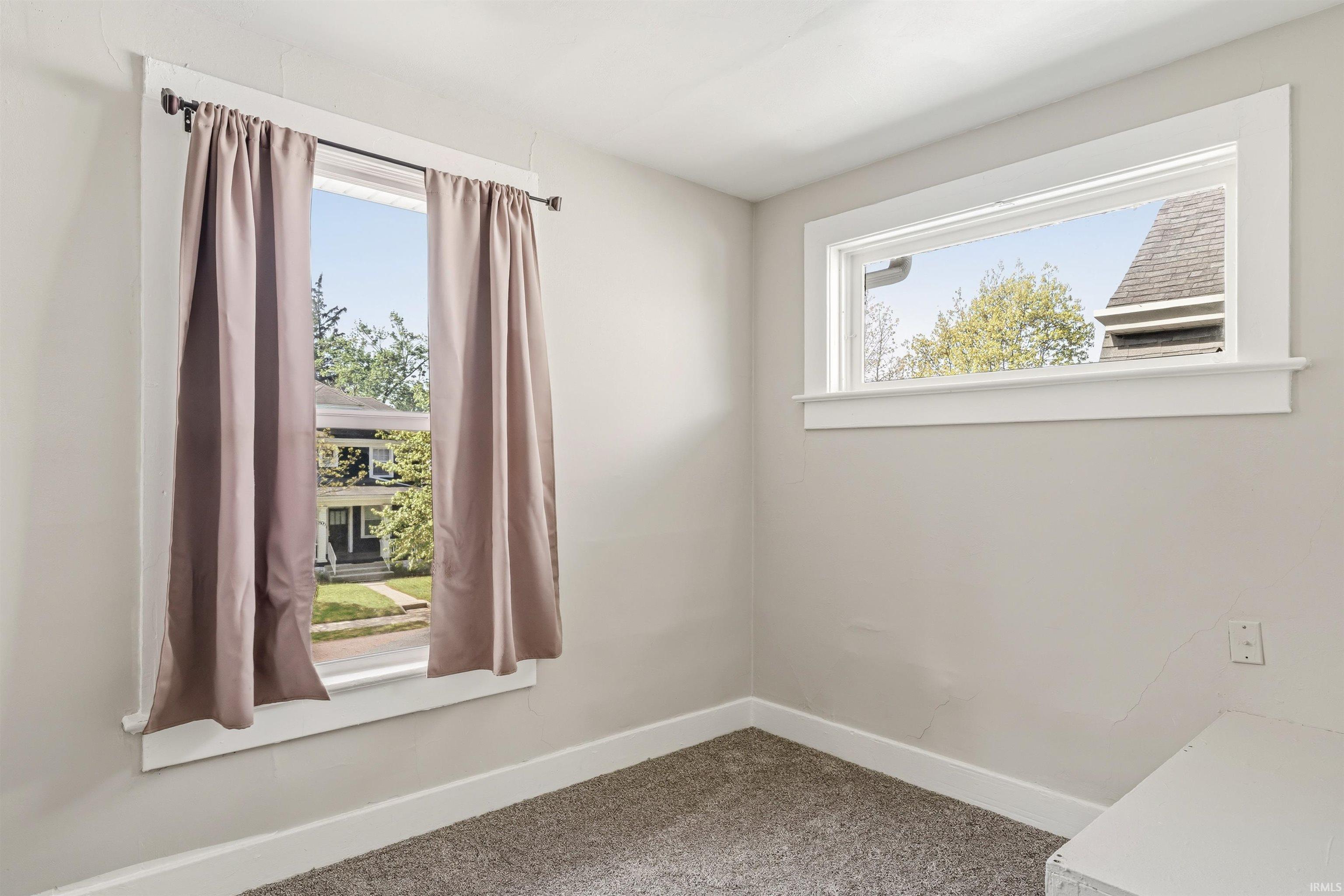 Carpeted room featuring two windows with white trim, light gray walls, and white baseboards