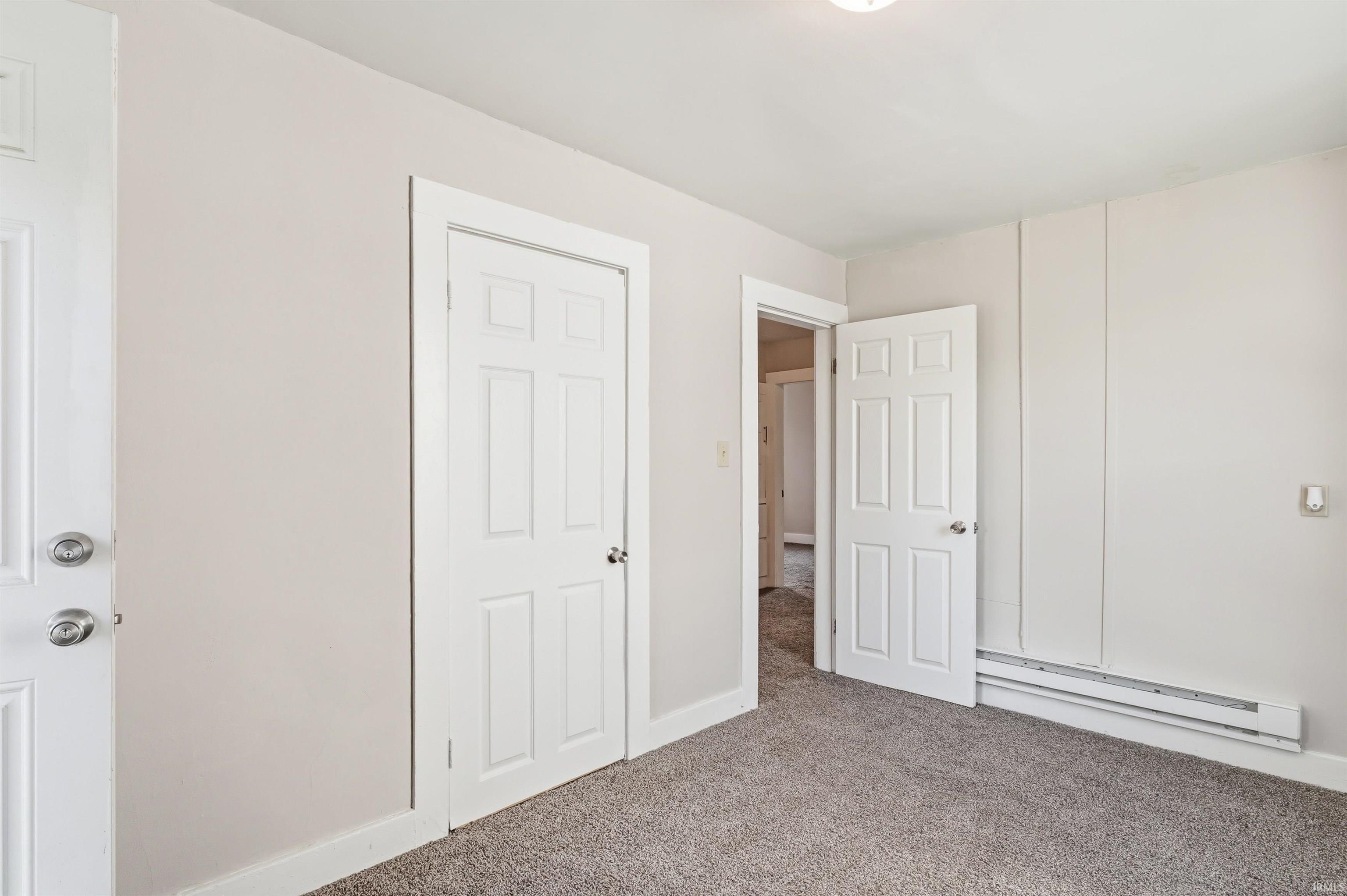 Light gray carpeting provides a neutral foundation for this room, featuring light beige walls and white trim