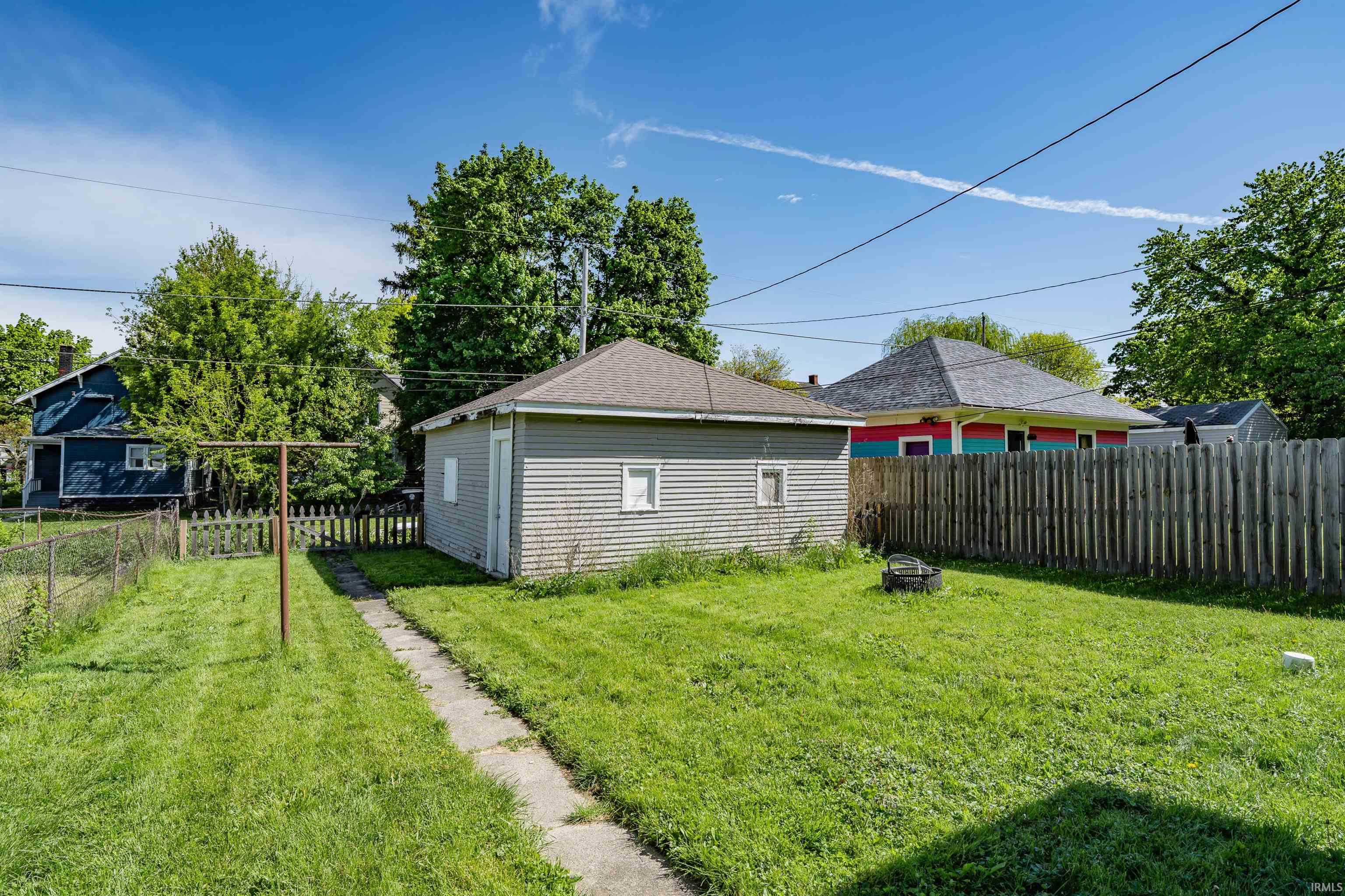 Spacious backyard featuring a detached garage with horizontal siding, a concrete pathway, and a wooden privacy fence