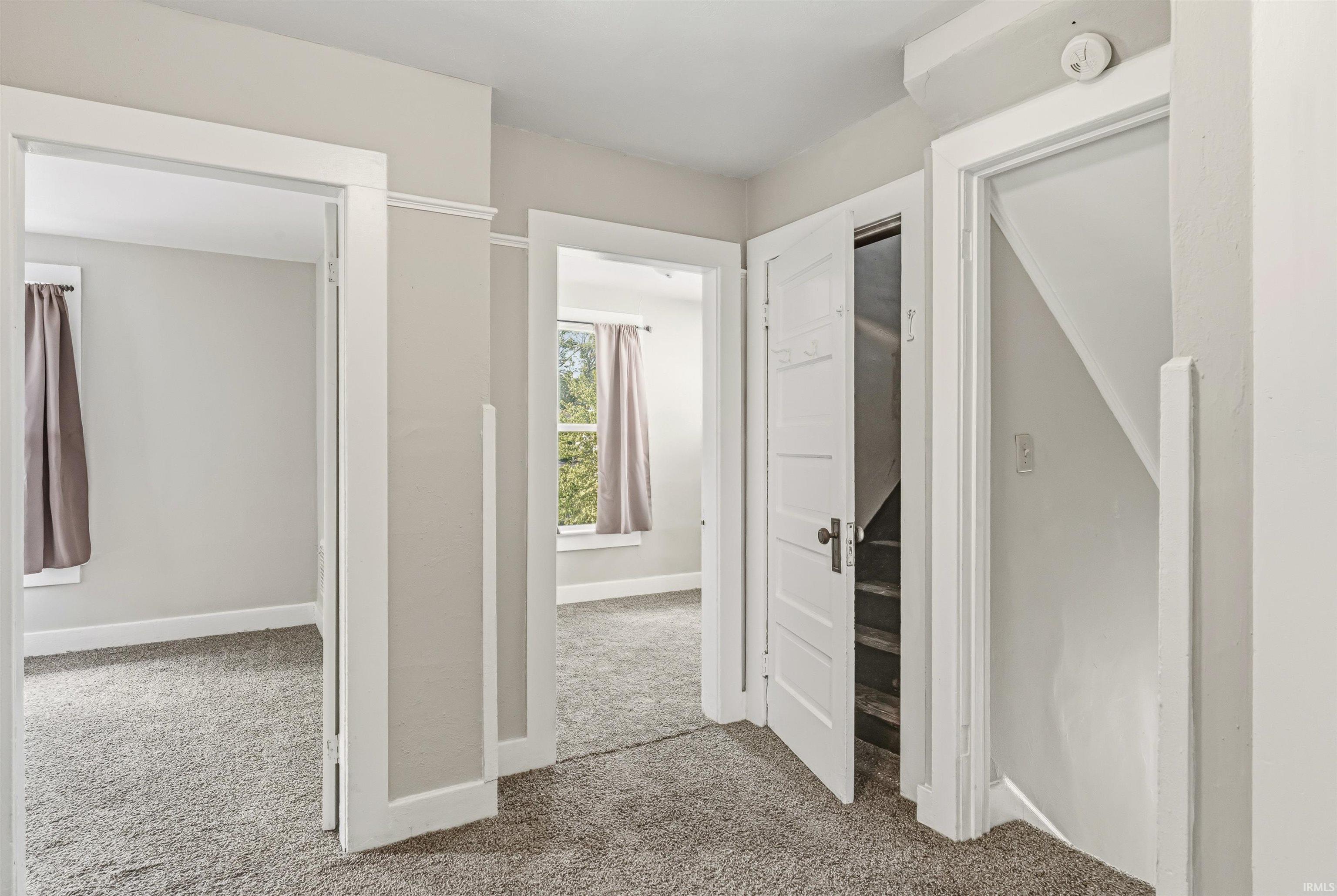 Hallway featuring neutral-toned walls, light gray carpet flooring, and white trim