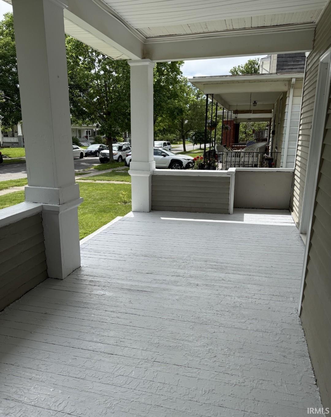 Covered front porch featuring a painted wood-finish floor and white structural columns