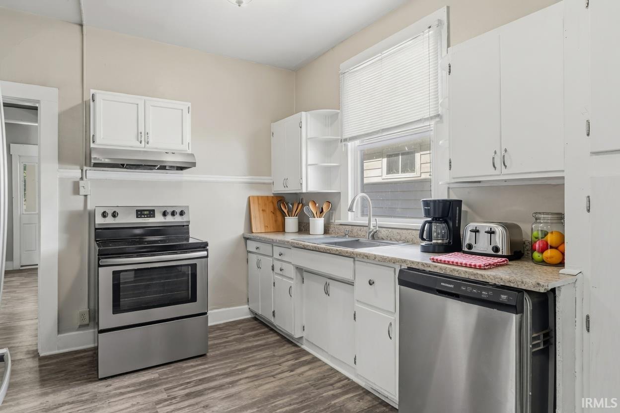 Kitchen featuring white cabinetry, light-toned countertops, a stainless steel electric range, a stainless steel dishwasher, and wood-finish flooring