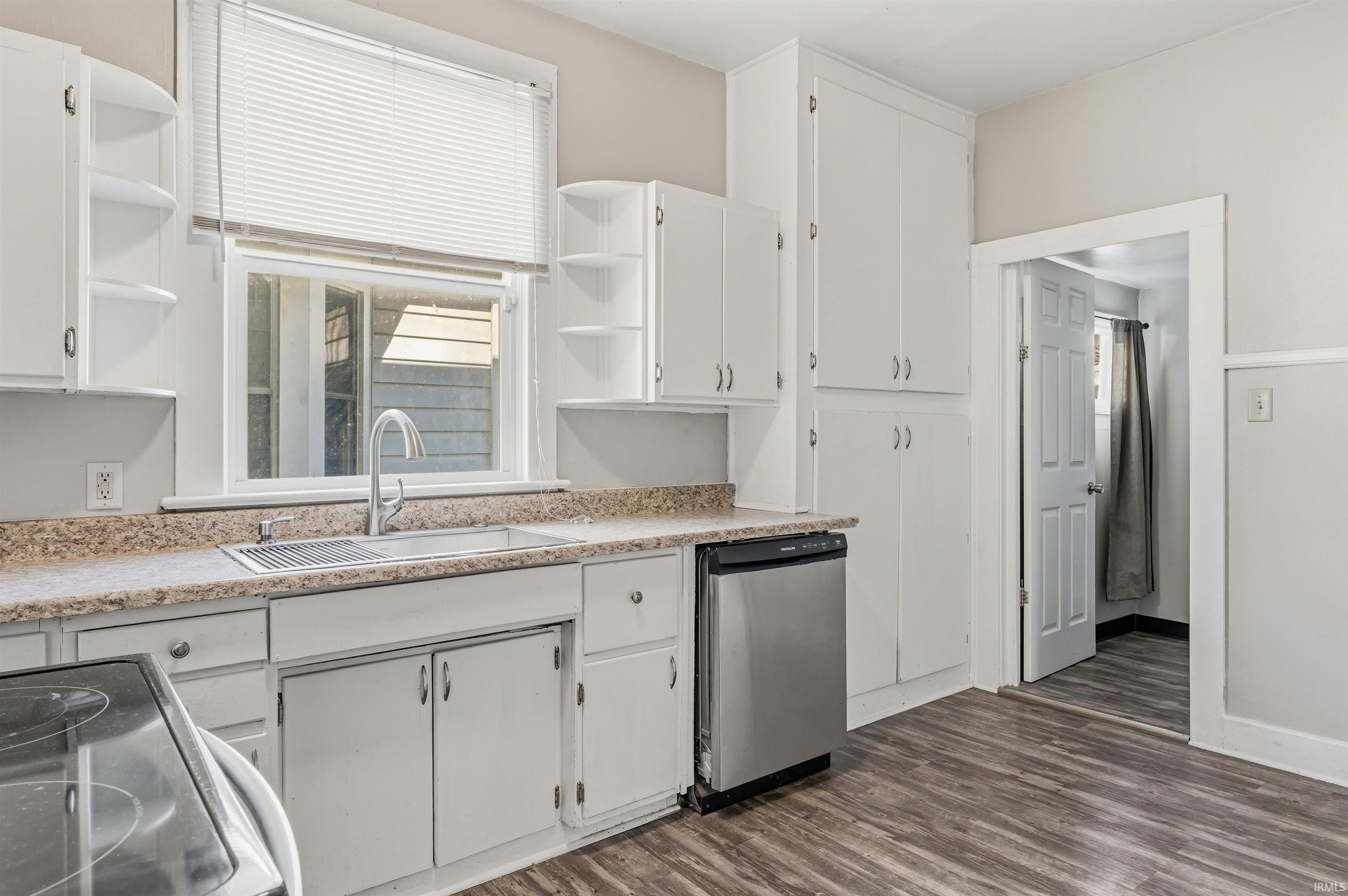 Kitchen featuring white cabinetry, wood-finish flooring, and a stainless steel dishwasher
