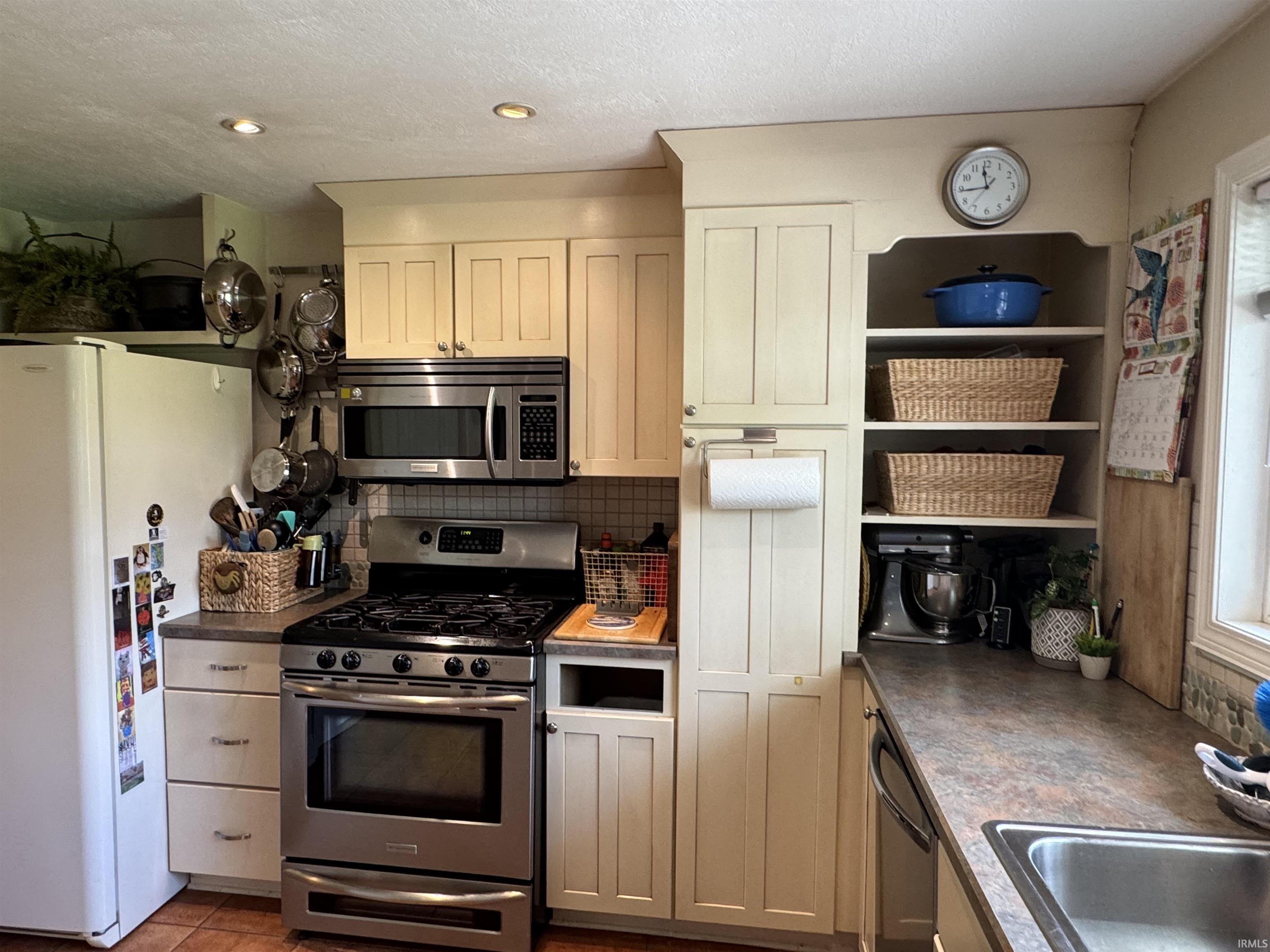 Kitchen featuring cream cabinetry, stainless steel oven with gas range, stainless steel microwave, stone-finish countertops, and recessed lighting