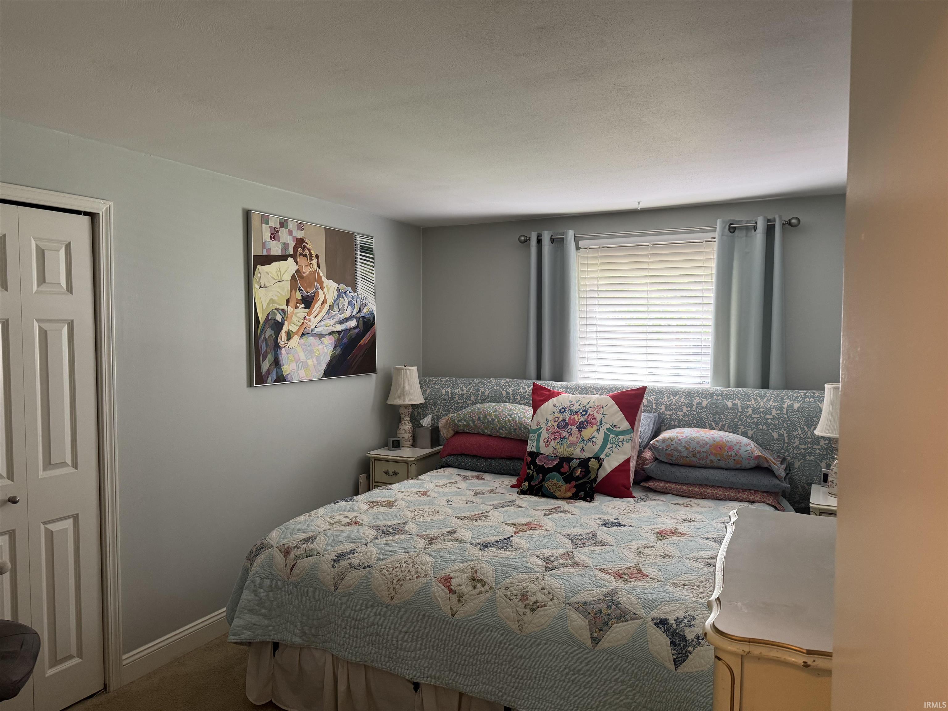Interior room featuring light gray walls, a window with horizontal blinds, and a bi-fold closet door
