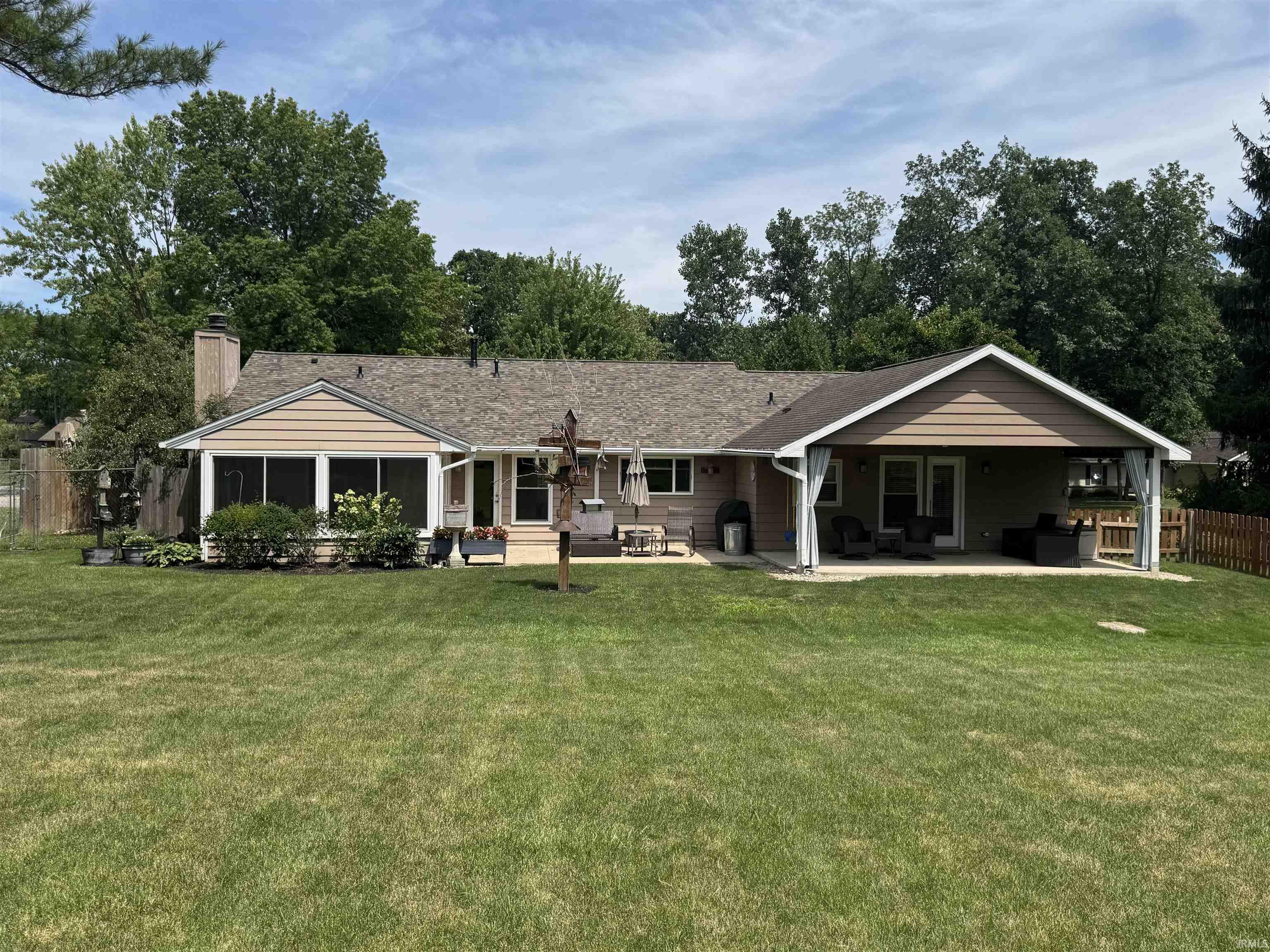 Expansive green lawn with a composite shingle roof, a screened-in porch, a covered patio, and a privacy fence