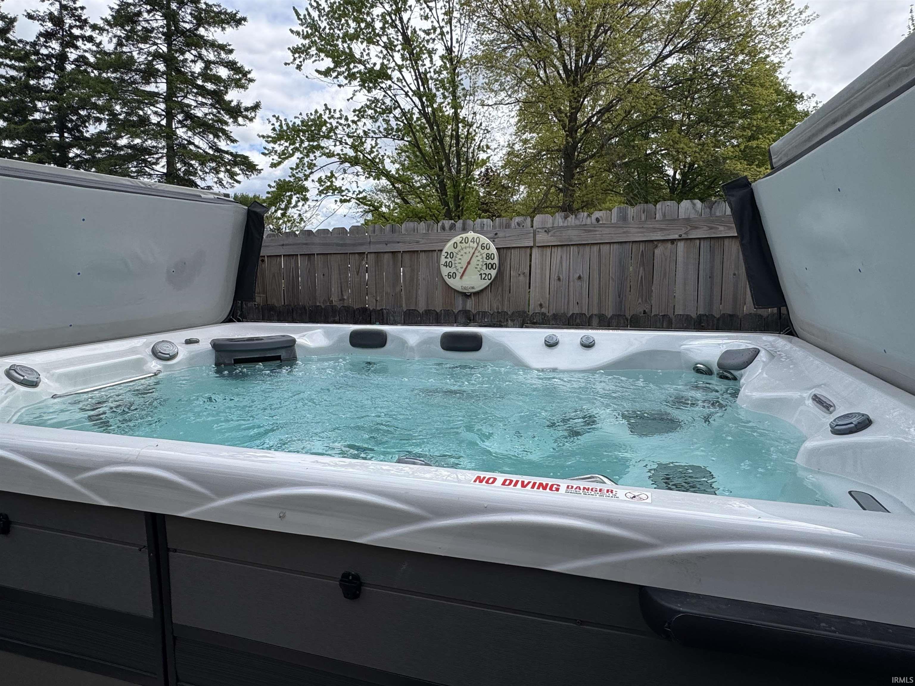 Outdoor spa with active jets, featuring a light gray exterior and a partial privacy fence