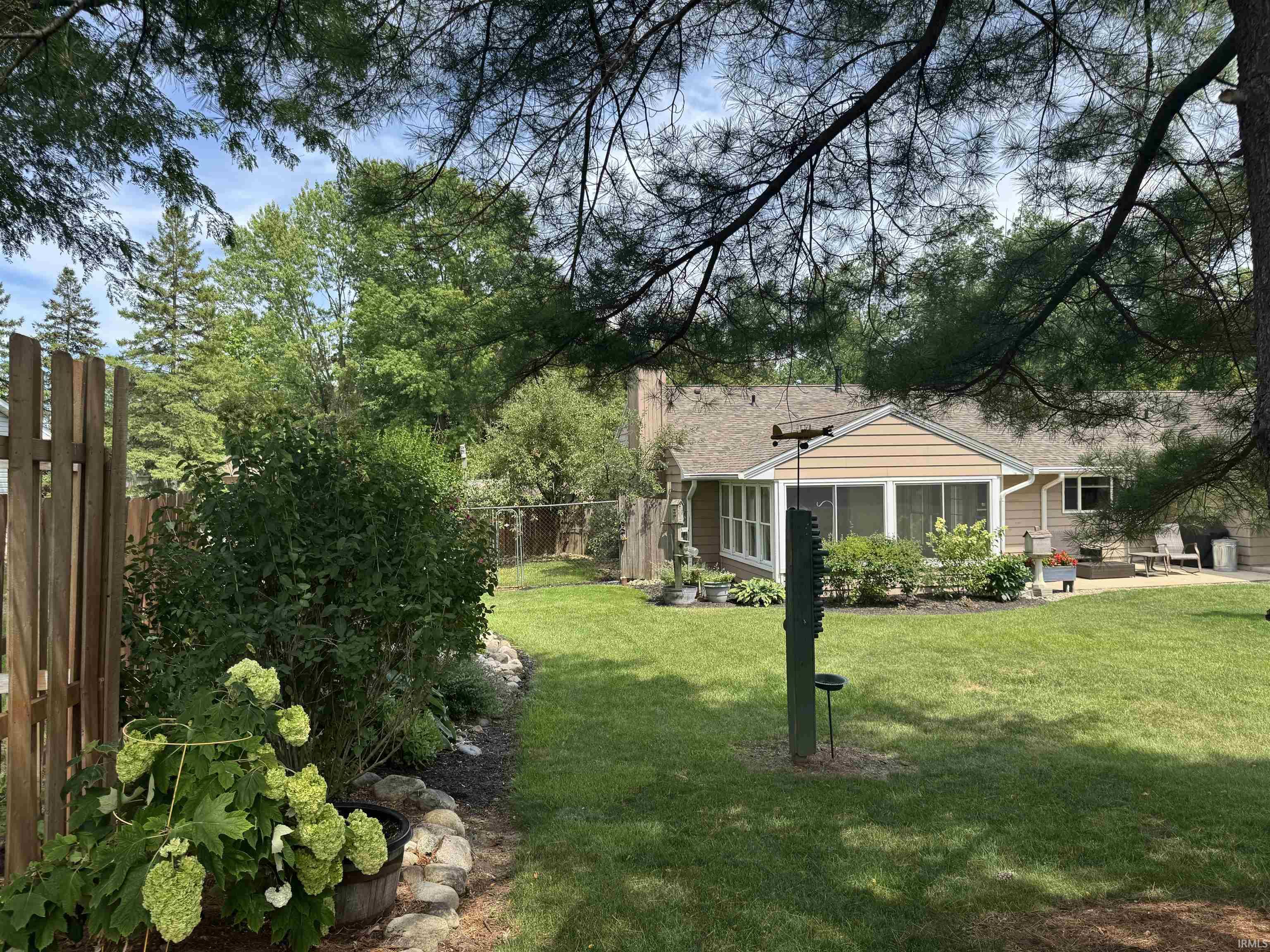 Expansive backyard featuring a manicured lawn, established landscaping, privacy fencing, and a patio area