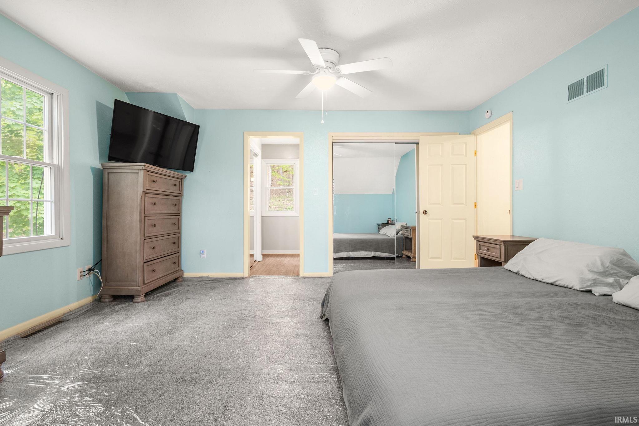 Spacious room featuring light blue walls, gray textured flooring, and a ceiling fan with integrated lighting