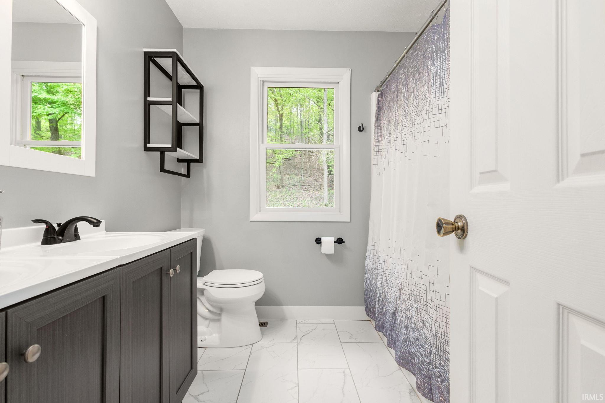 Bathroom featuring a modern vanity with dark cabinetry, white countertop, and matte black faucet