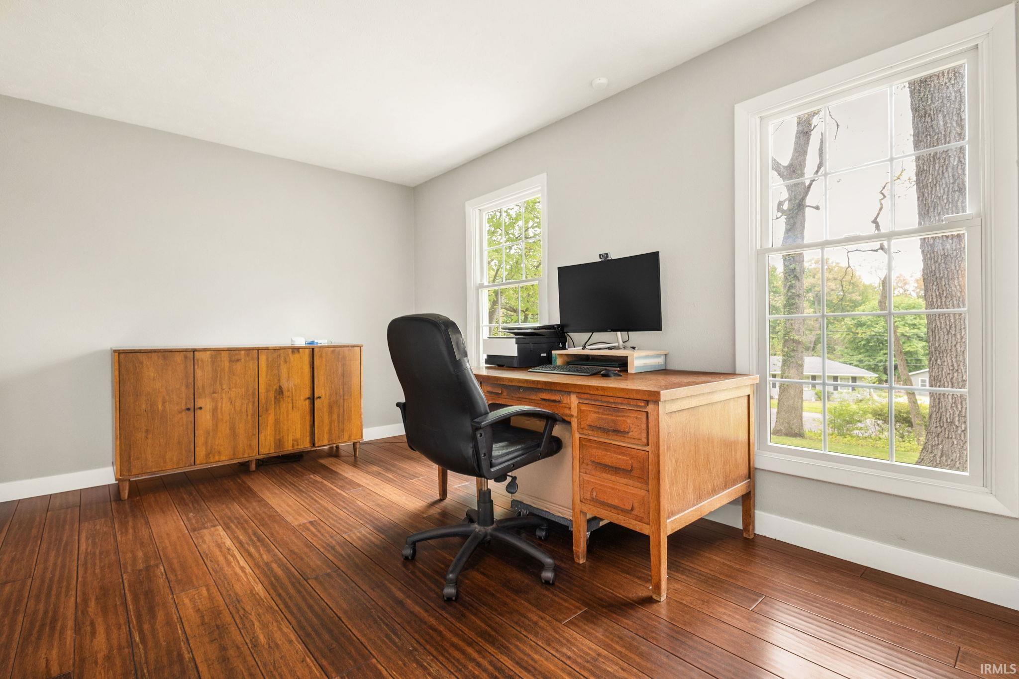 Spacious room featuring rich wood-finish flooring, light gray wall paint, and white trim