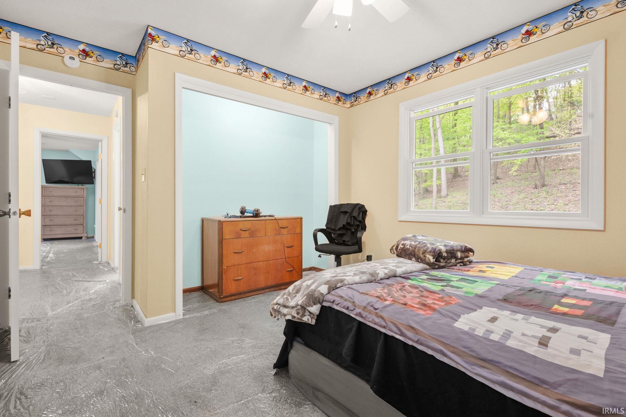 Room featuring a dual-pane window, ceiling fan, and light-toned walls with decorative border