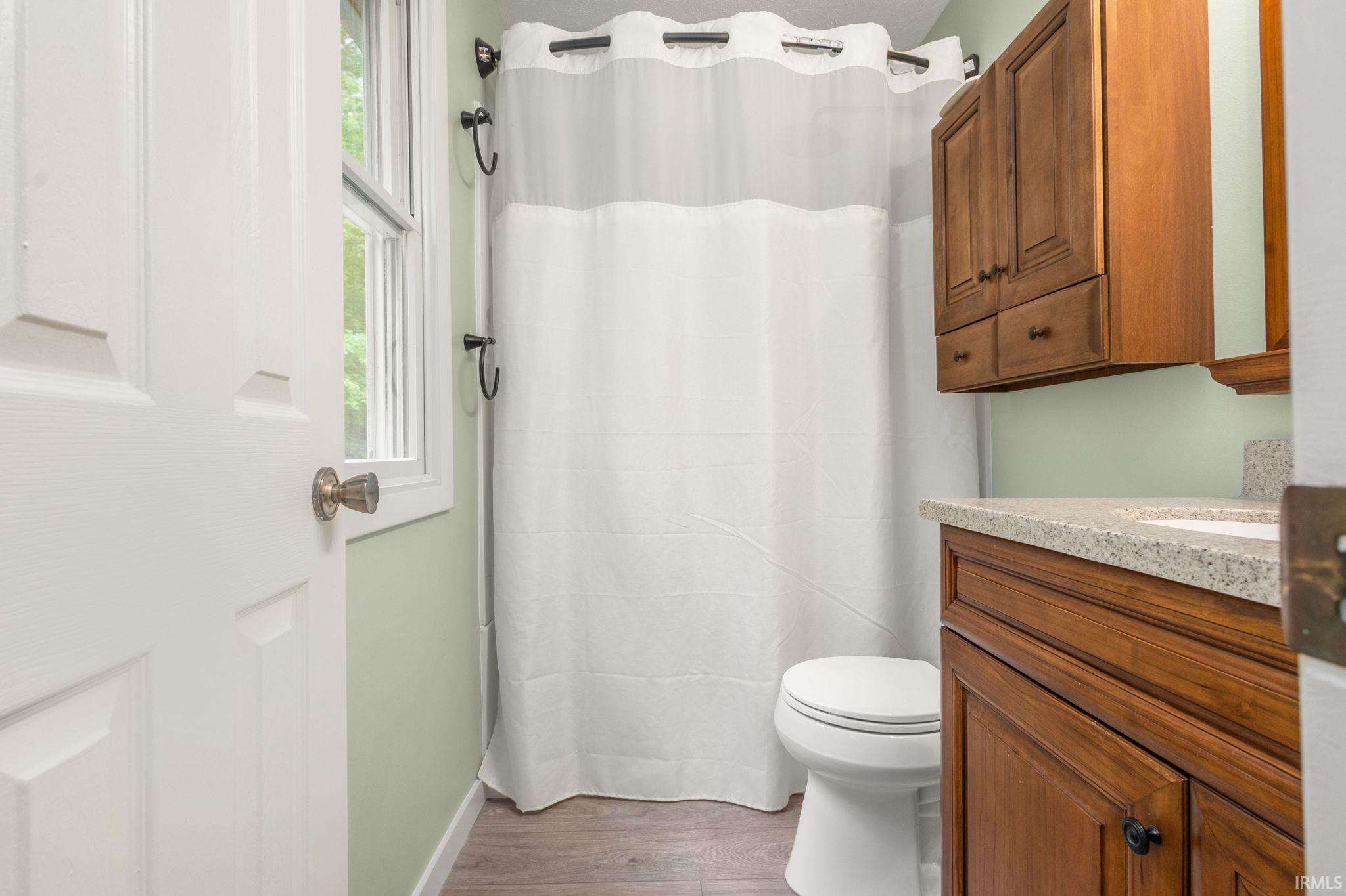 Bathroom featuring a wood-finish vanity with a speckled countertop and an integrated sink, complementing a wood-finish upper cabinet