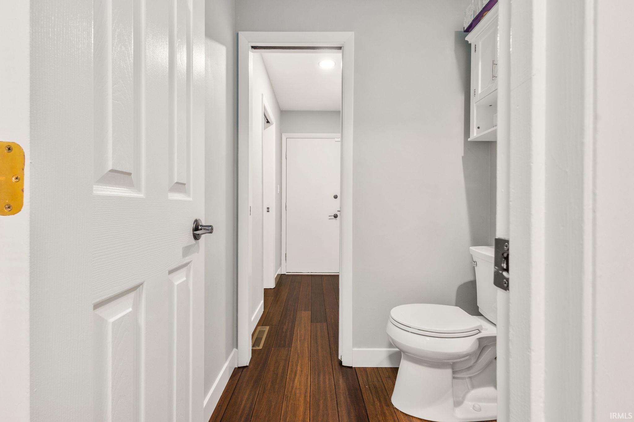 Hallway featuring wood-finish flooring, light grey walls, and white trim