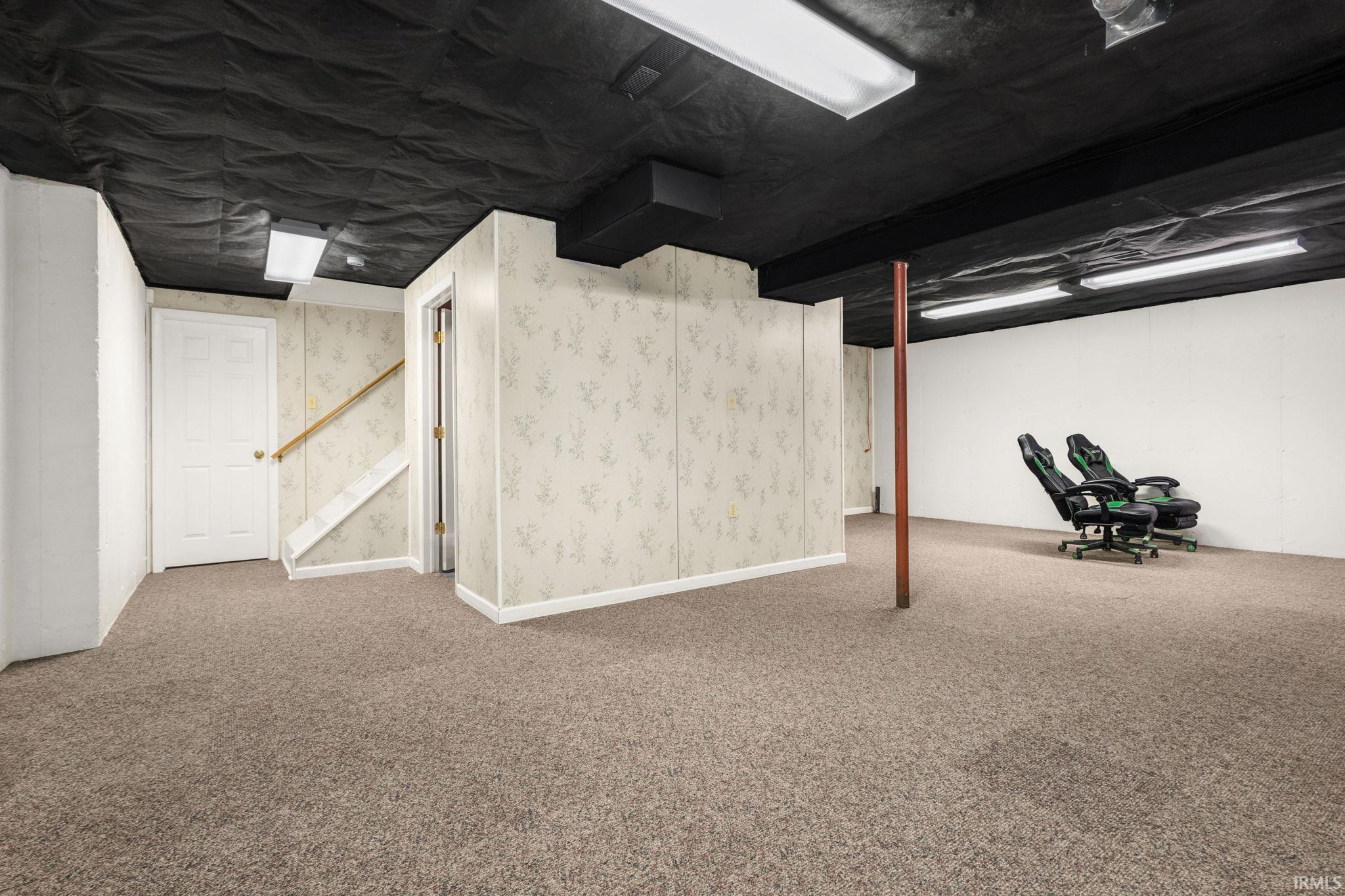 Finished lower-level space featuring carpet flooring, painted ceilings, and fluorescent lighting