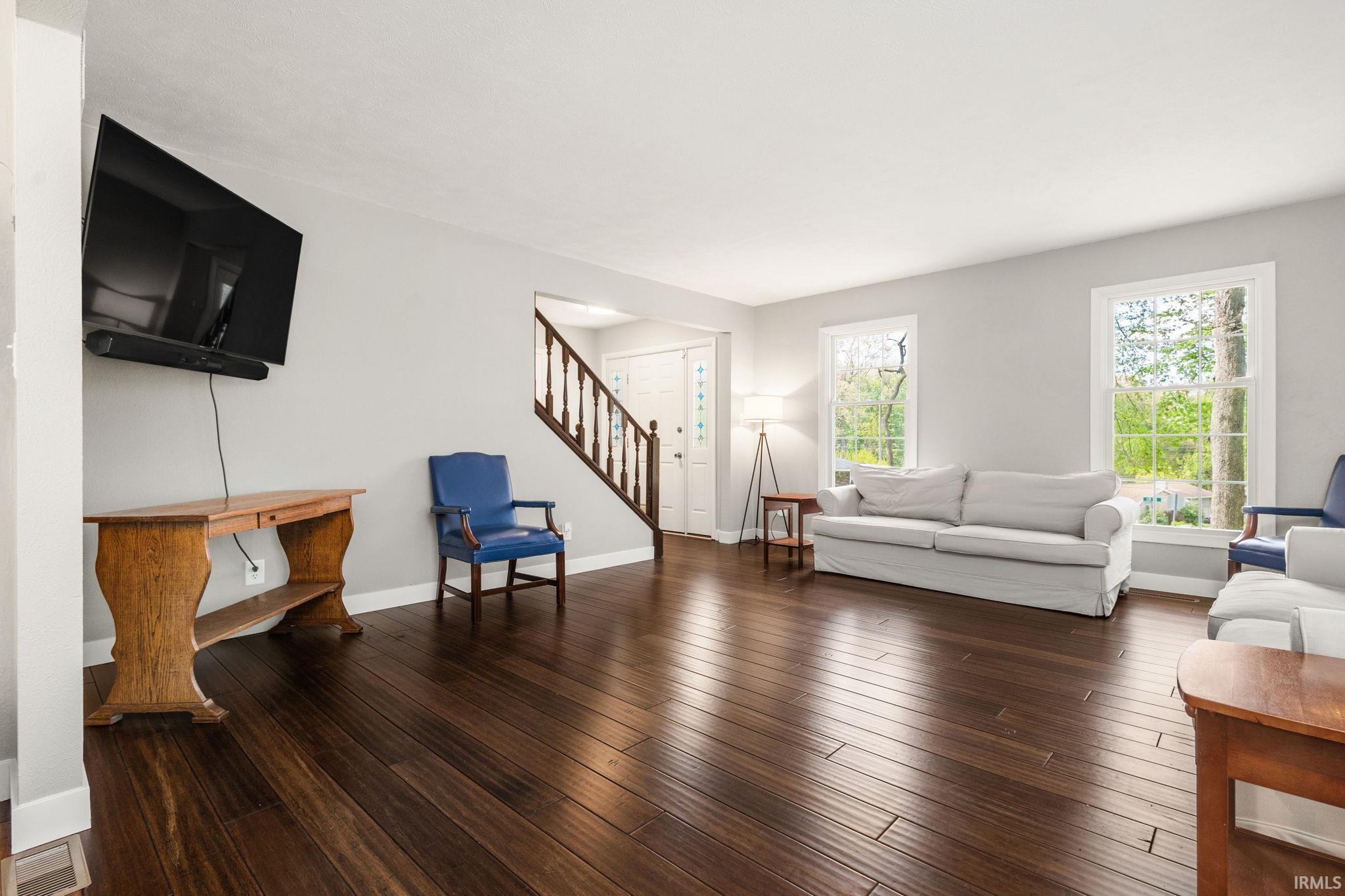 Spacious living area featuring rich wood-finish flooring and light gray walls