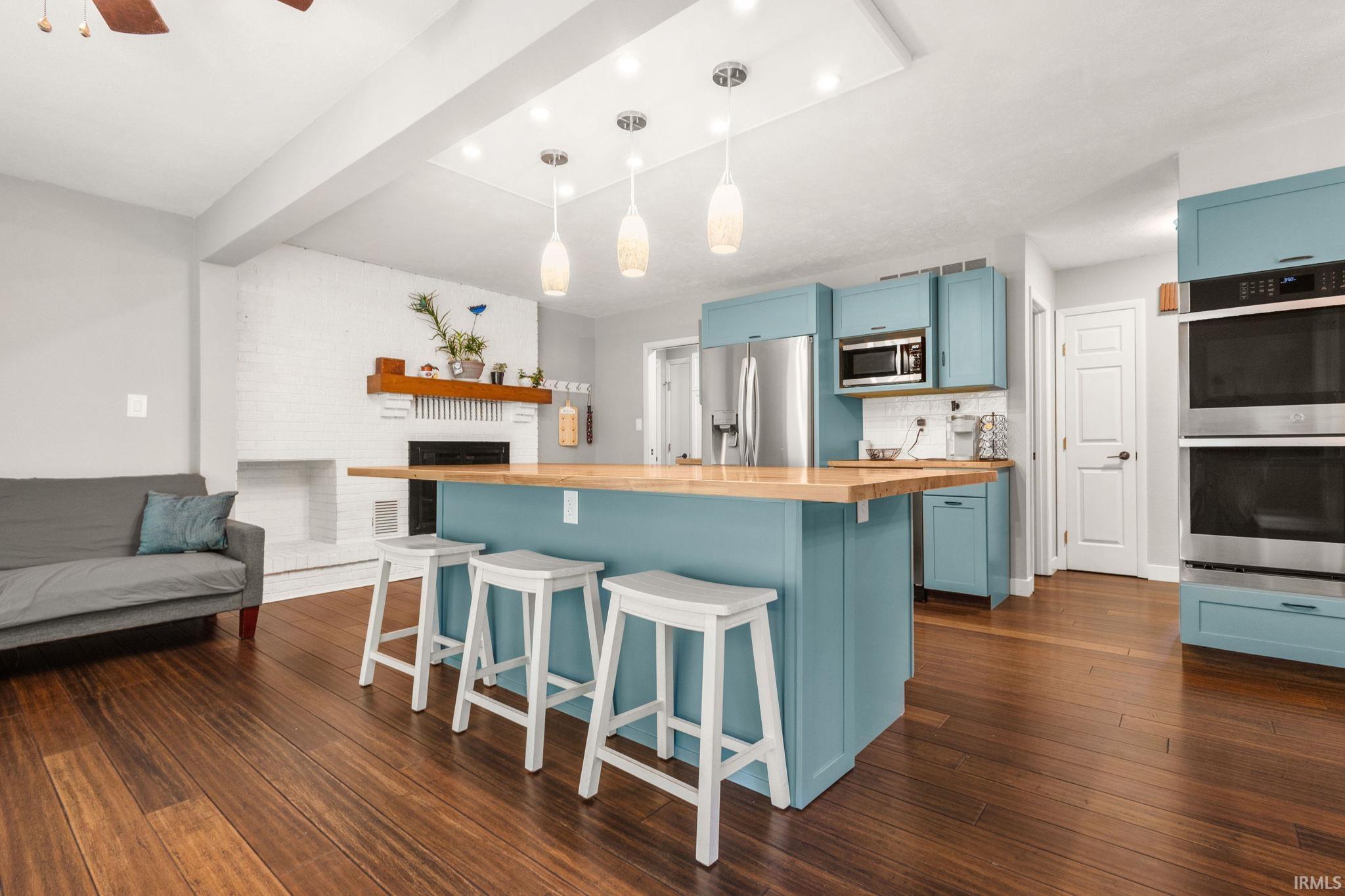 Kitchen featuring a large island with a wood-finish countertop, pendant lighting, and abundant blue cabinetry