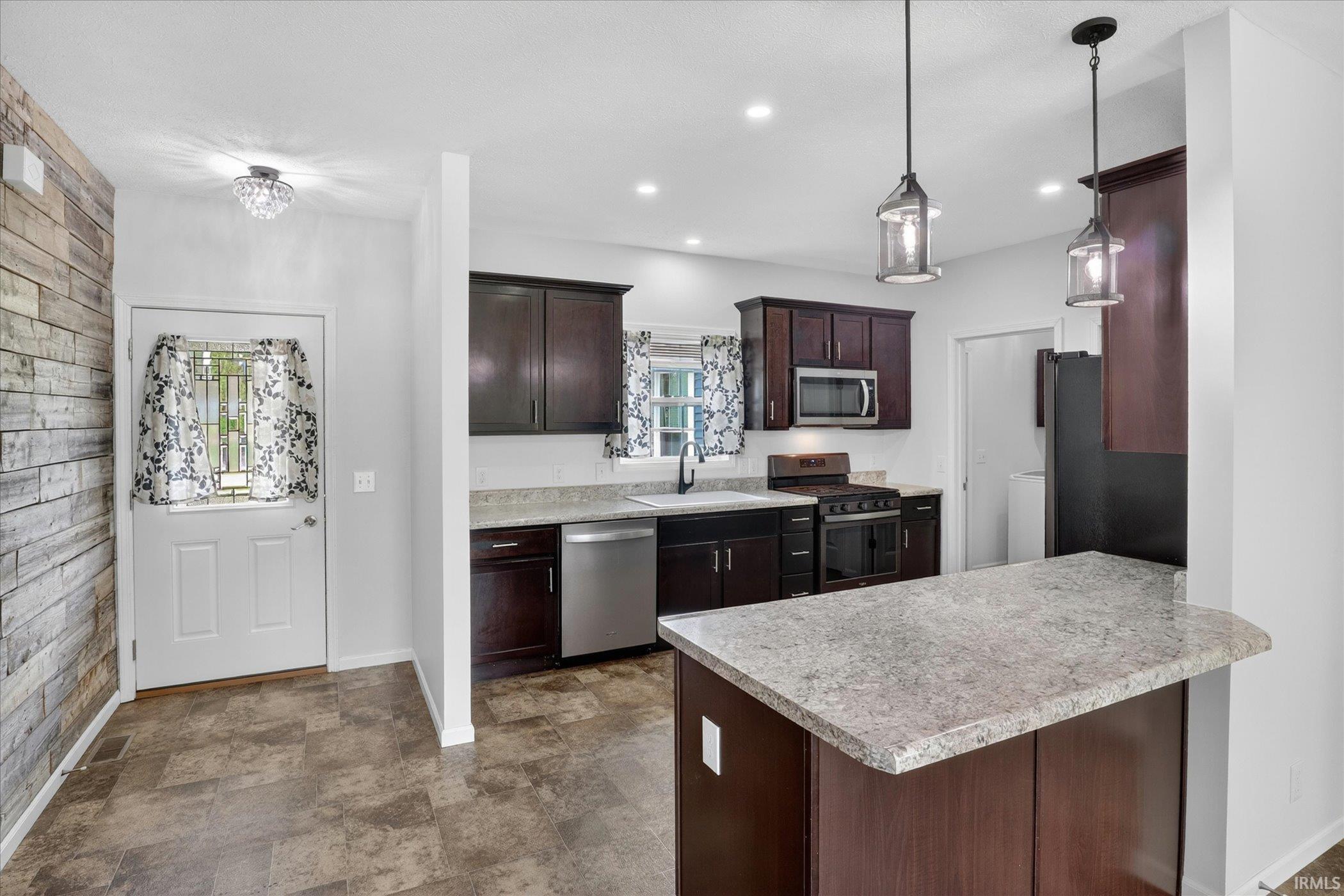 Kitchen featuring dark wood-finish cabinetry, light-toned countertops, and stainless steel appliances