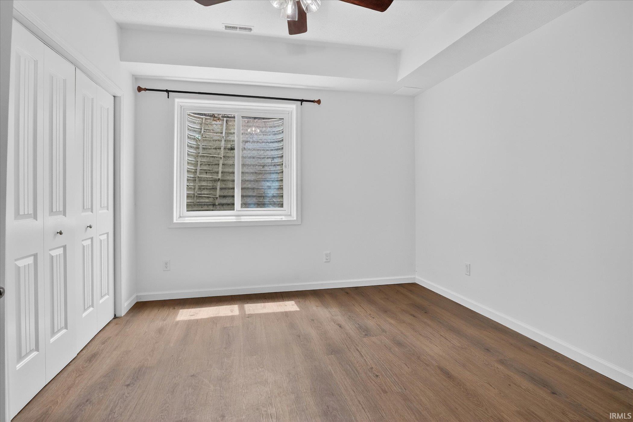Spacious room featuring wood-finish flooring, a white trim window, and neutral wall tones