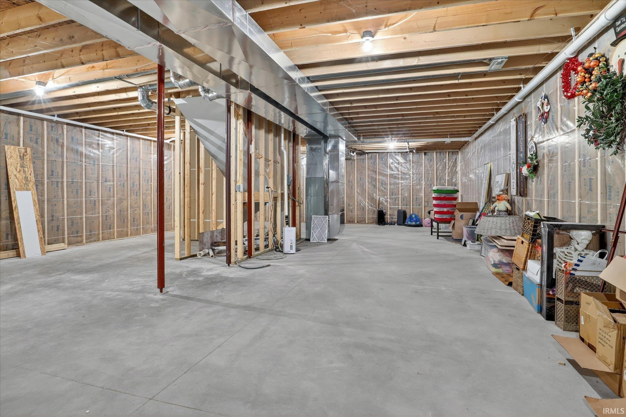 Unfinished basement offering substantial expansion potential, featuring exposed ceiling joists, concrete flooring, and framed walls
