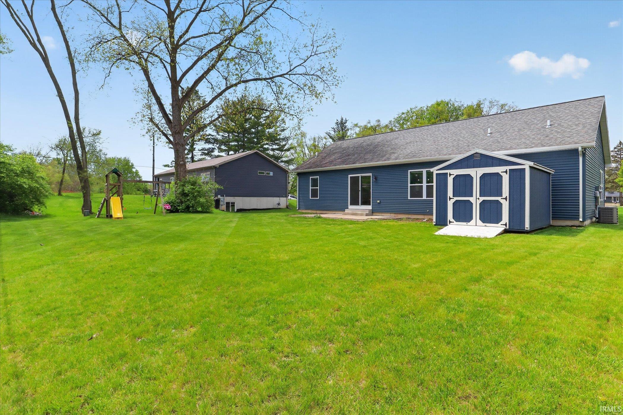 Expansive green lawn with mature trees and a blue-sided exterior