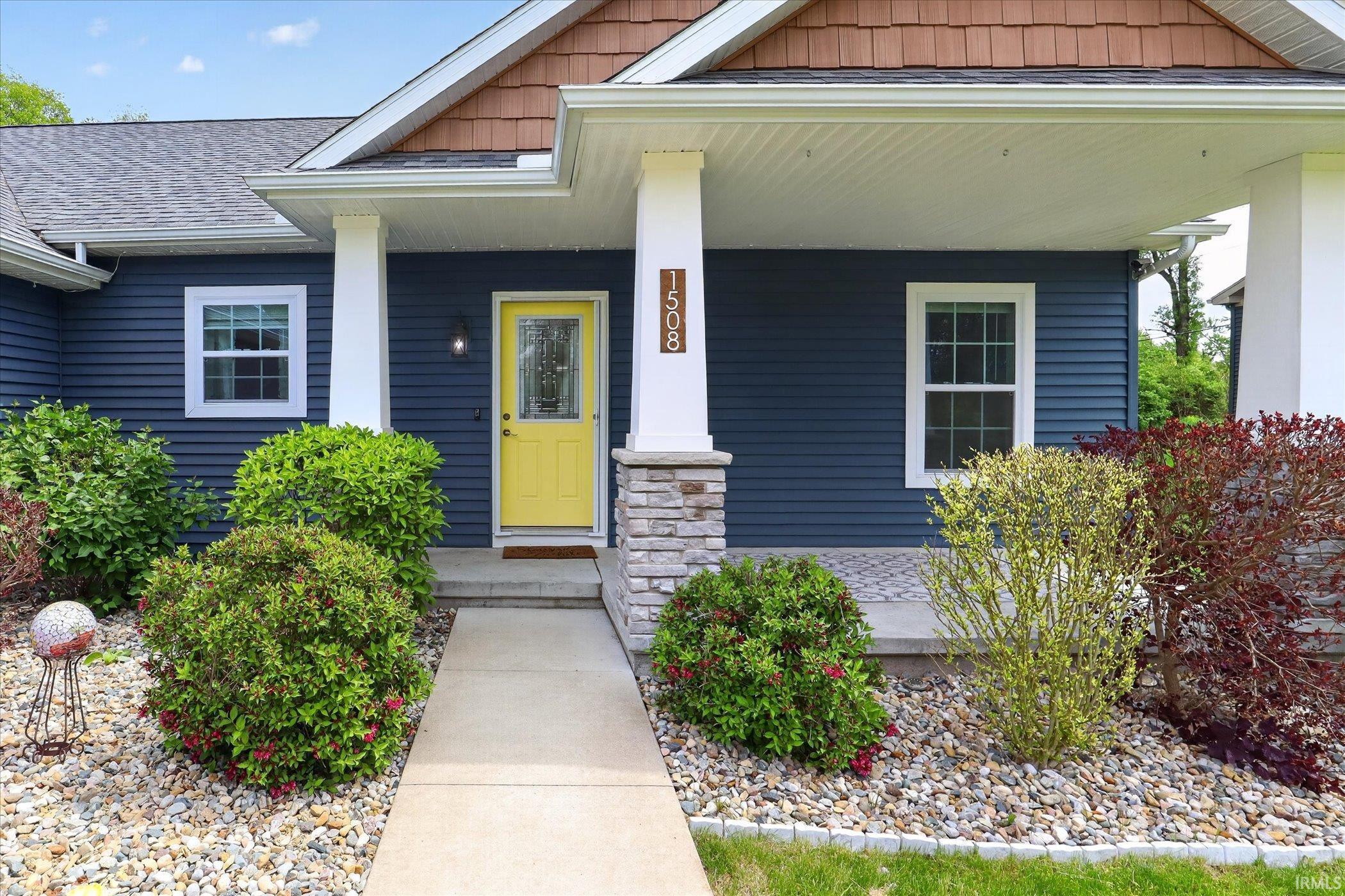 Exterior featuring blue siding, a covered porch with white columns, and stone accents