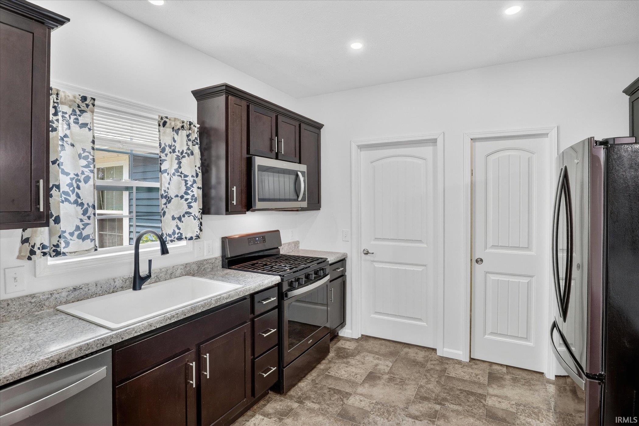 Kitchen featuring dark wood-finish cabinetry, light-toned countertops, and mosaic tile-look flooring