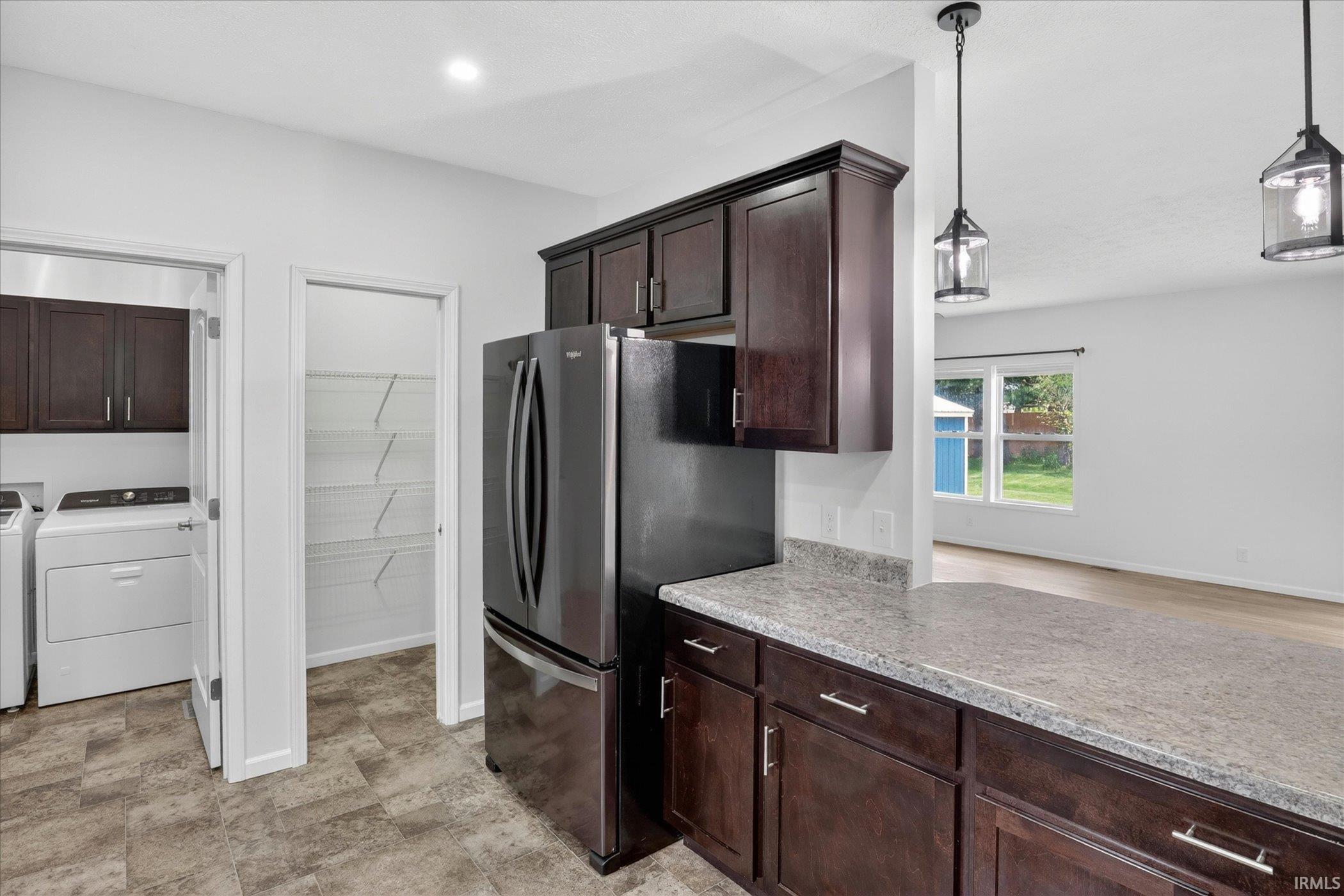 Kitchen featuring dark wood-finish cabinetry, light-toned countertops, and a modern refrigerator