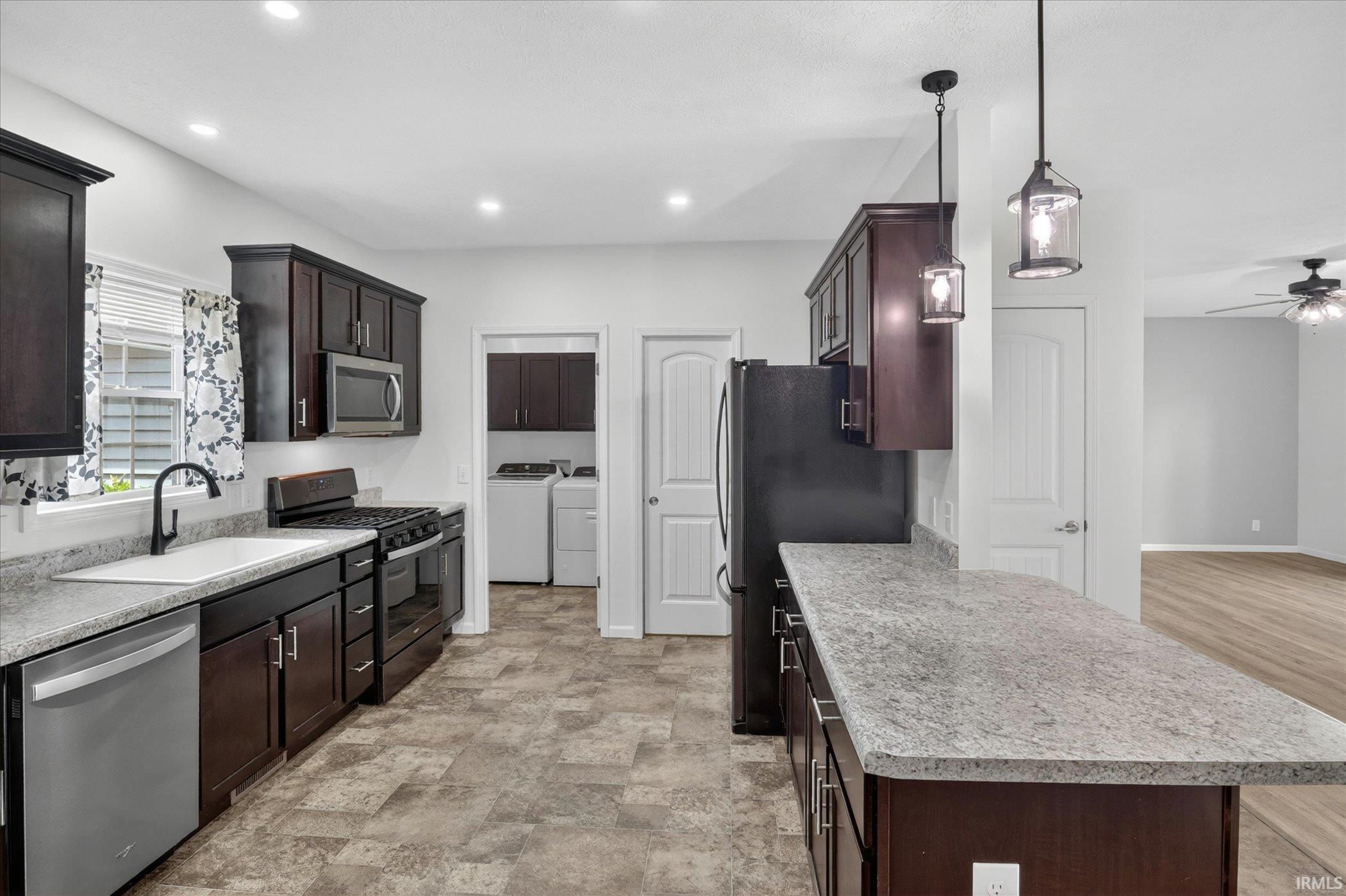 Kitchen featuring wood-finish cabinetry, stainless steel appliances, and light-toned countertops