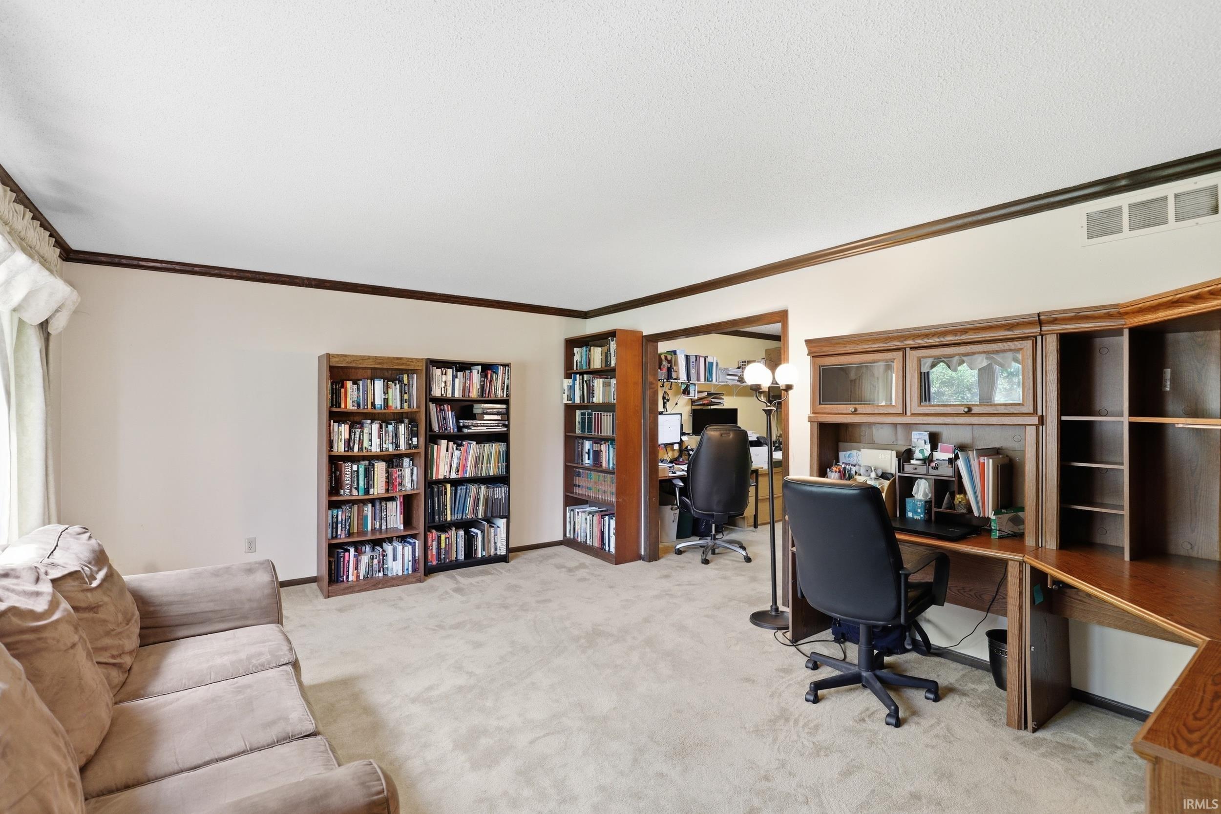 Dedicated office space featuring built-in wood-finish shelving and a wood-finish desk with upper cabinets