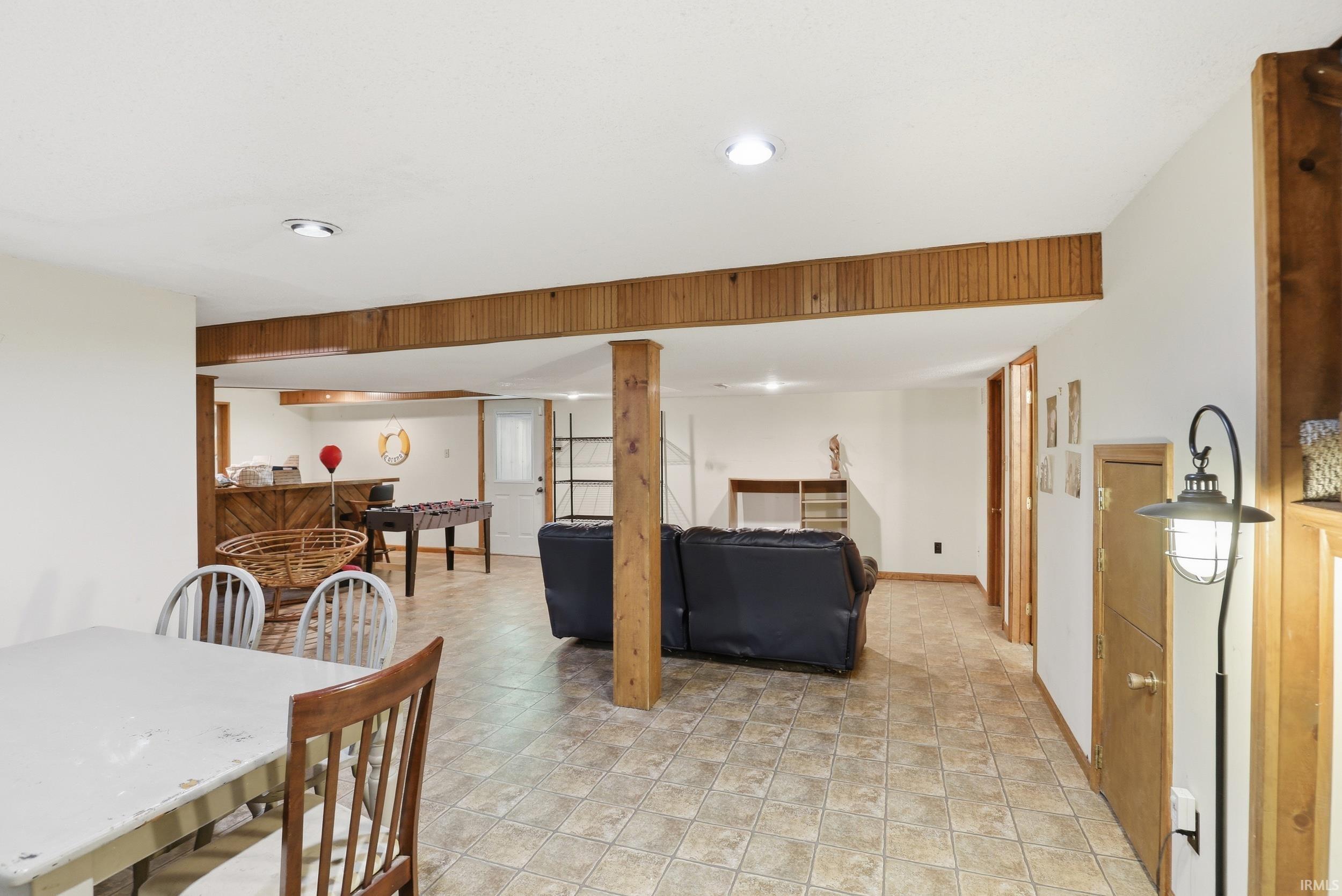 Spacious lower level featuring wood-finish ceiling beams, neutral wall paint, and recessed lighting