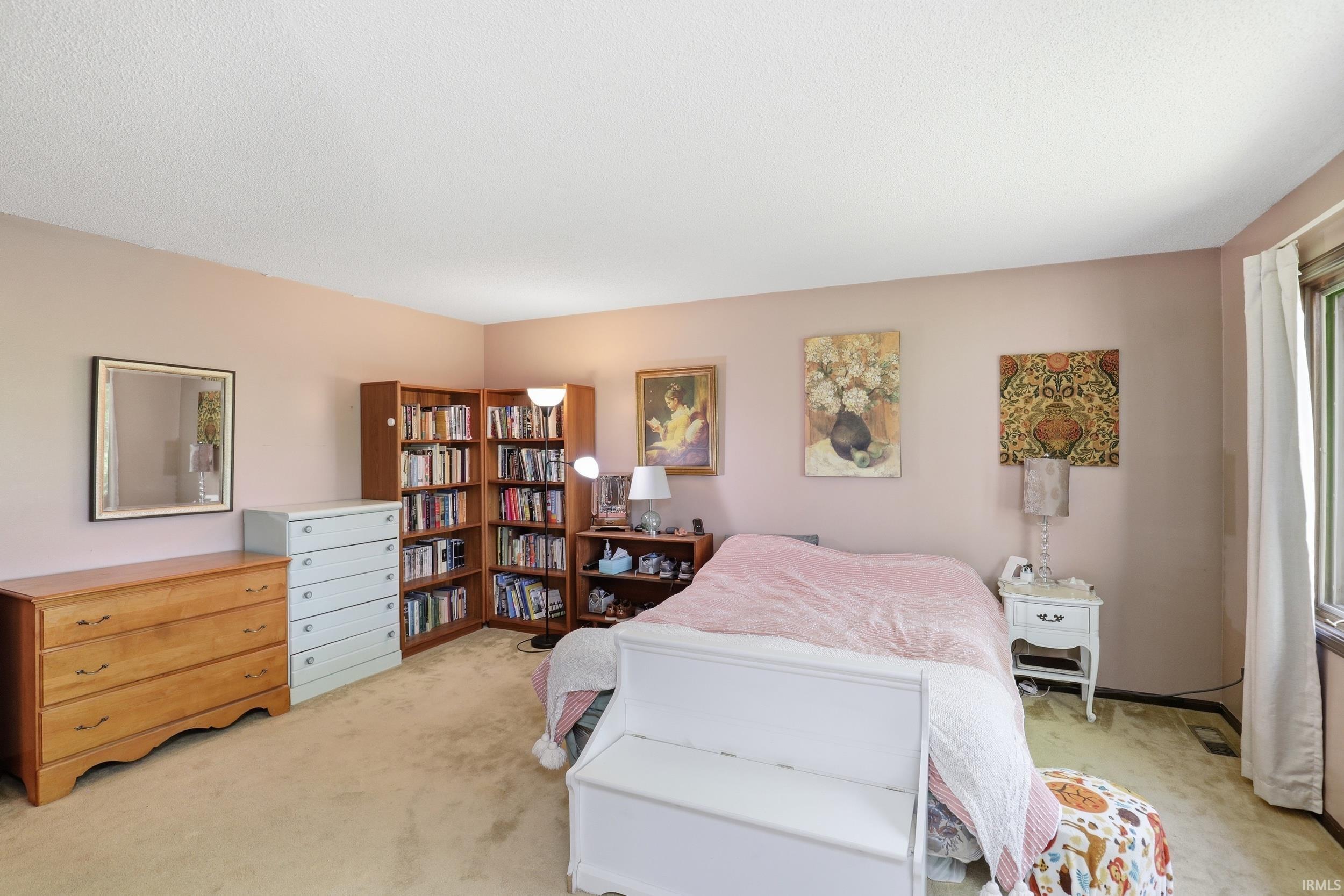 Carpeted room featuring a corner built-in bookcase, a window with curtains, and a light-colored ceiling
