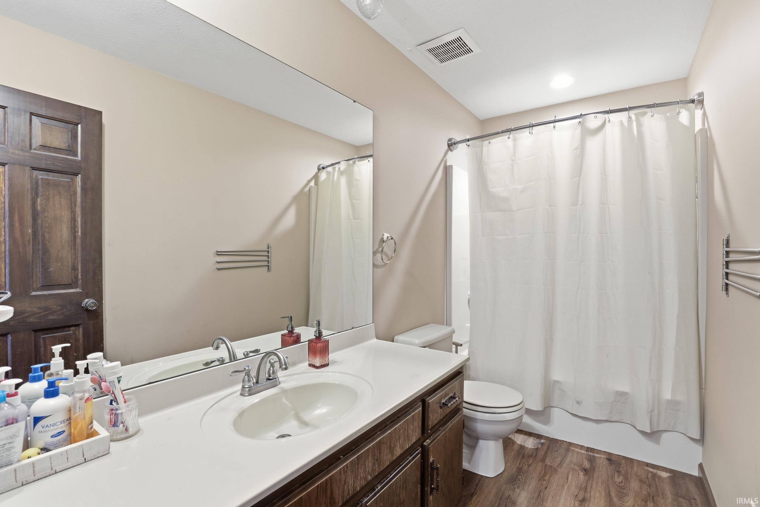 Bathroom featuring a single vanity with an integrated sink, laminate countertop, and wood-finish cabinetry