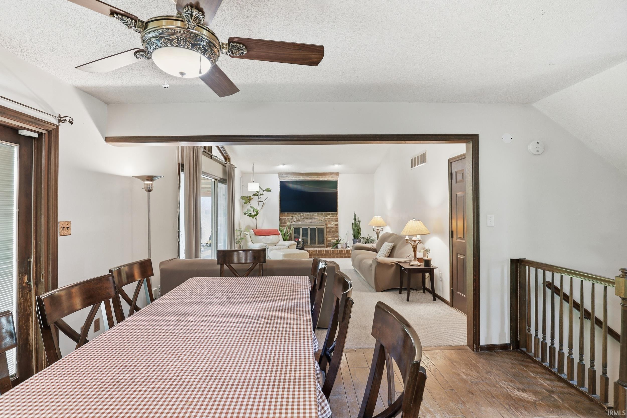 Open-concept living area featuring wood-finish flooring, a ceiling fan, and a wood-framed glass-paneled exterior door