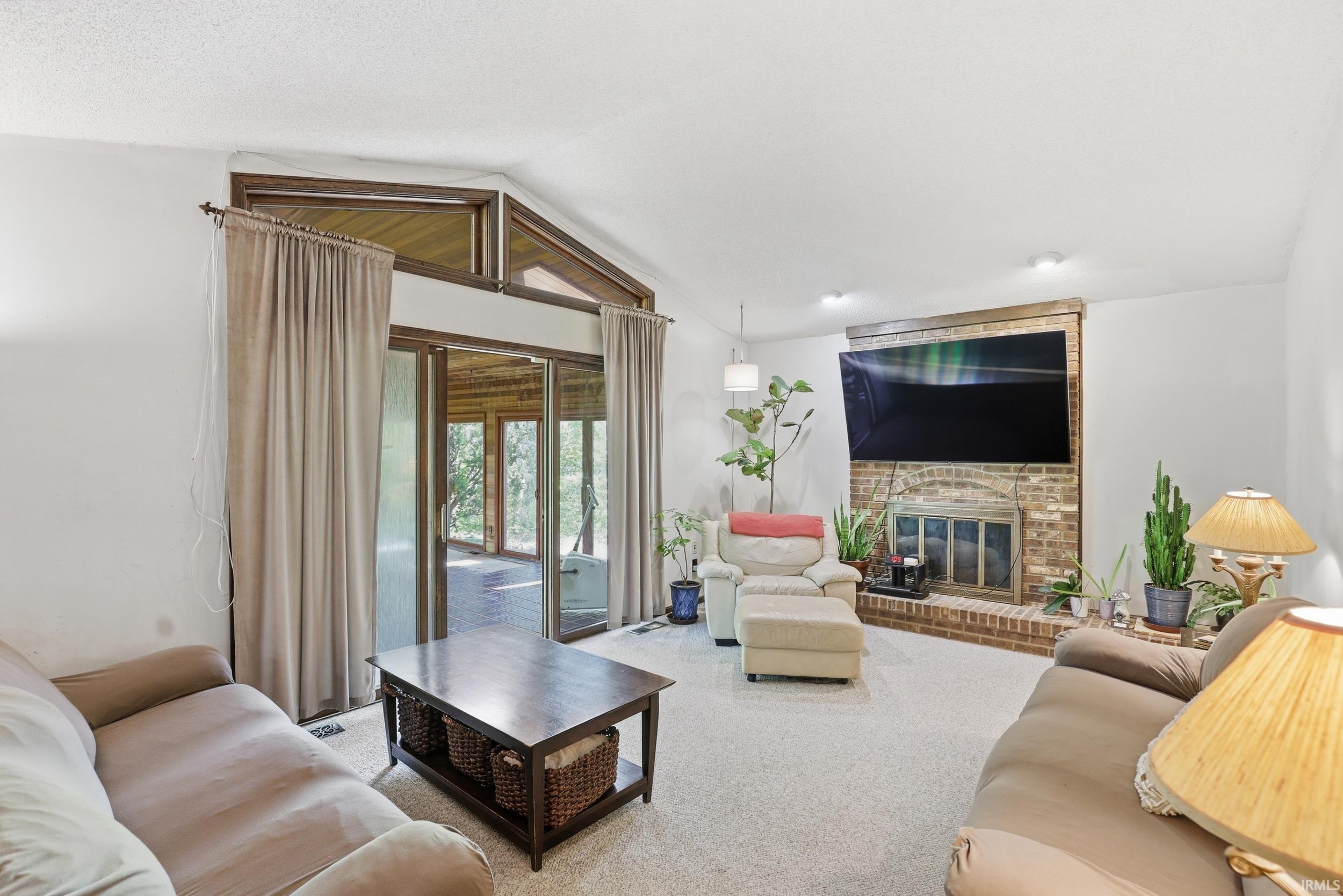 Living area featuring a brick-surround fireplace with a wood mantel, light carpeting, and recessed lighting