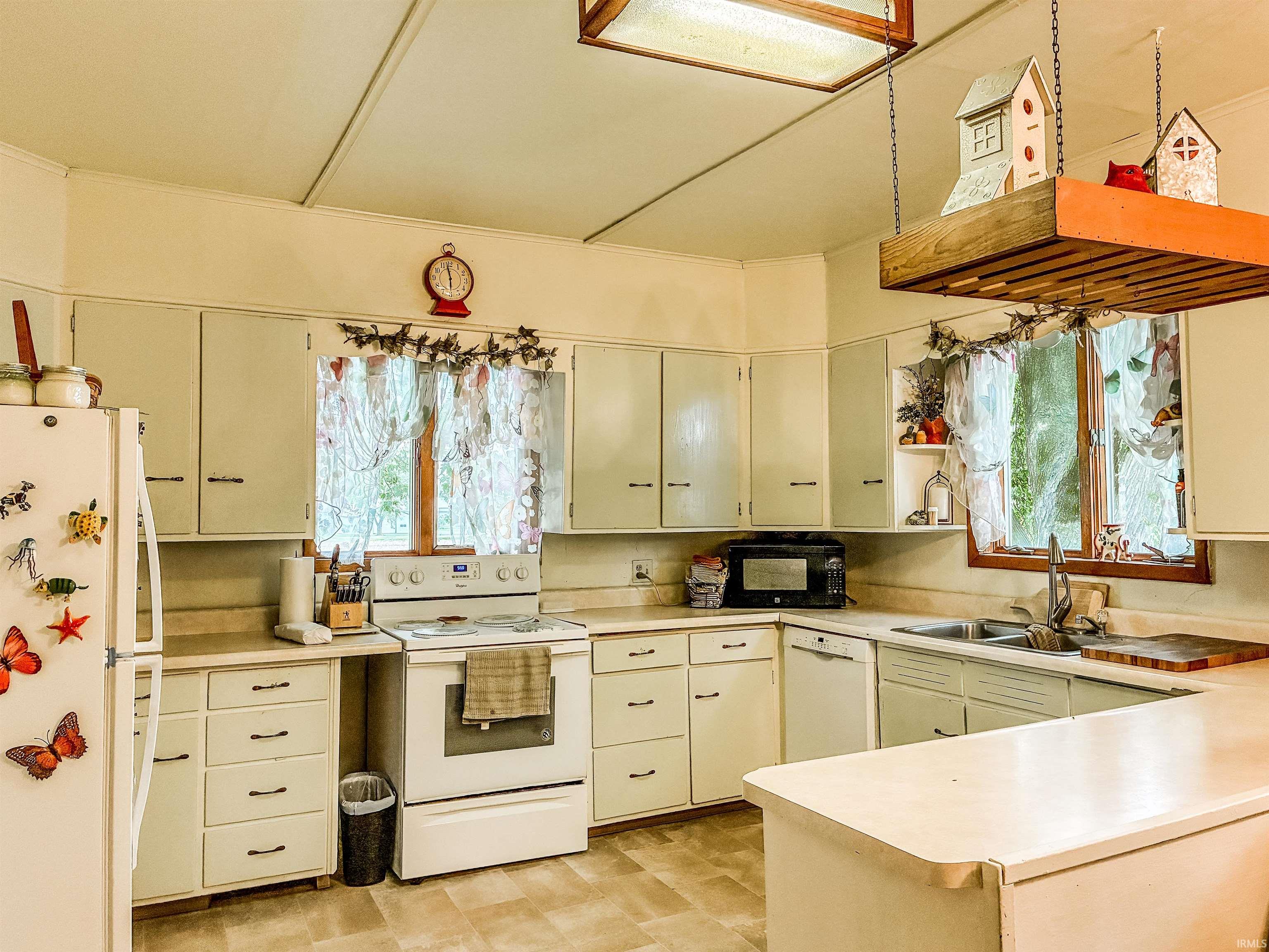 Kitchen featuring extensive cabinetry, laminate countertops, wood-frame windows, and tile flooring