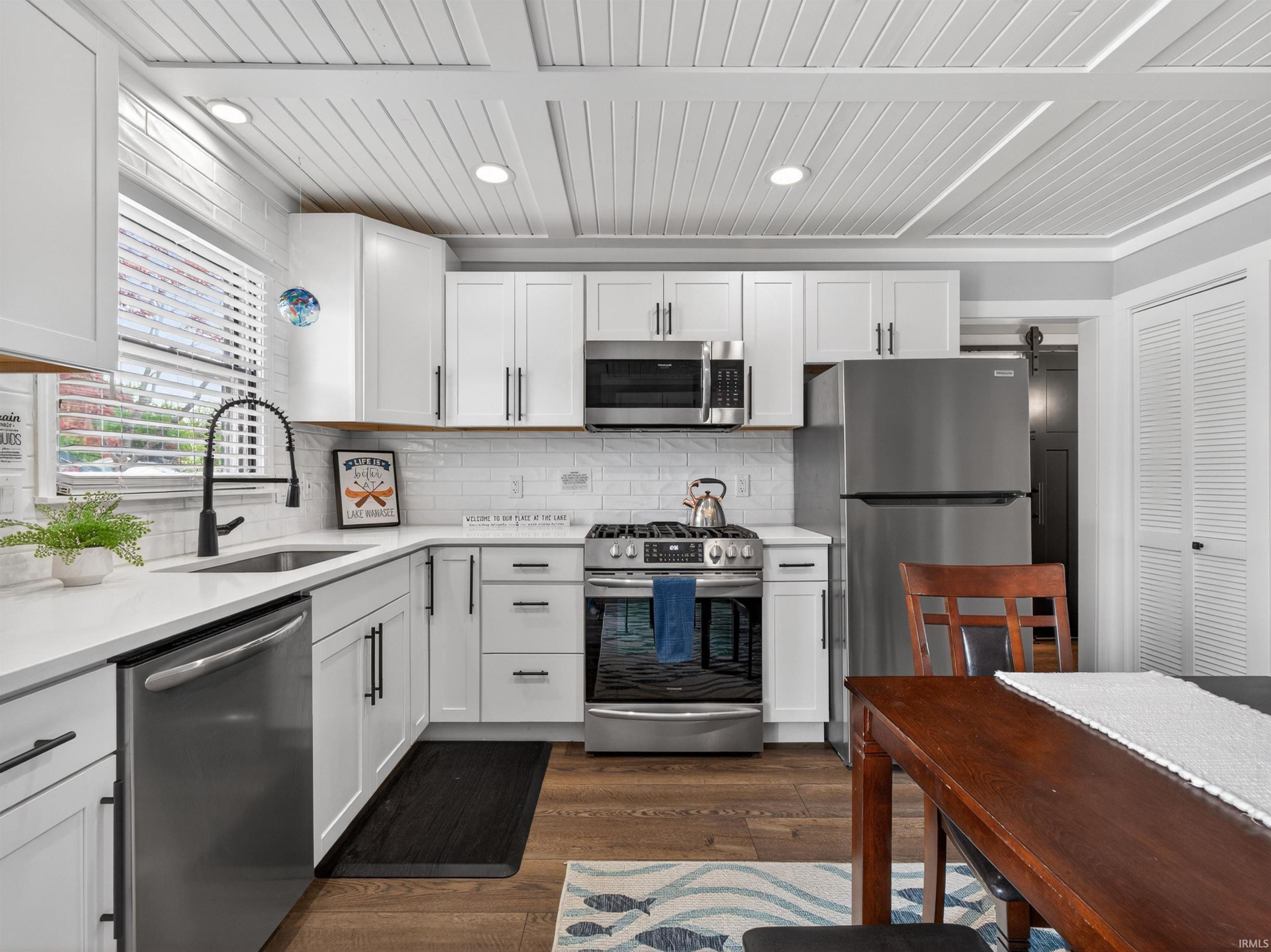 Kitchen featuring white cabinetry with matte black hardware, stainless steel appliances, and a white subway tile backsplash