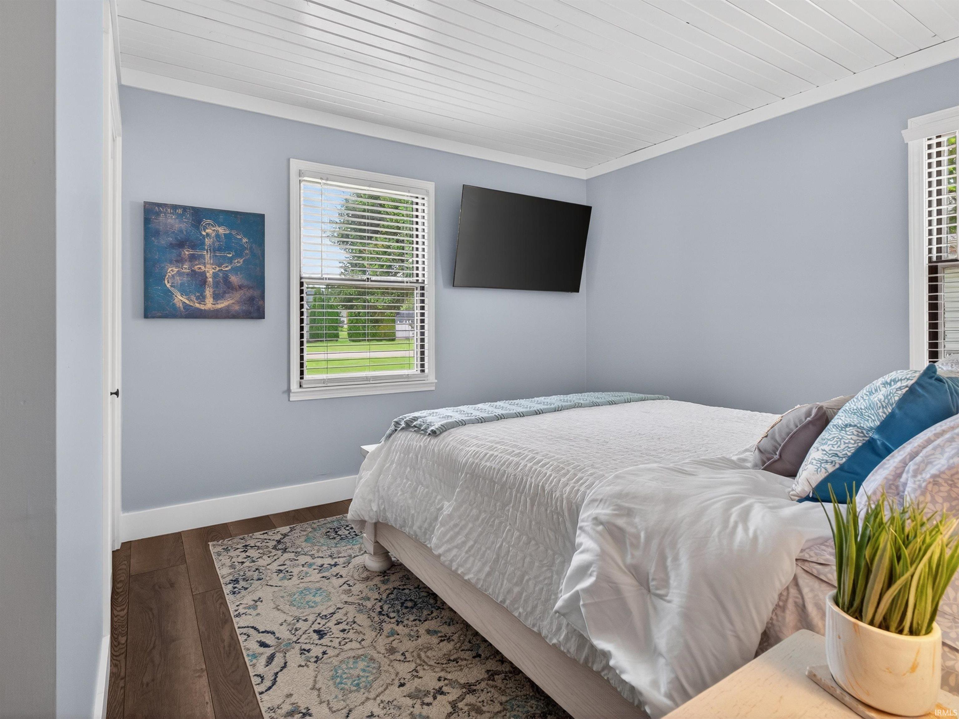 Bedroom featuring light blue walls, white tongue-and-groove ceiling, dark wood-finish flooring, and white trim