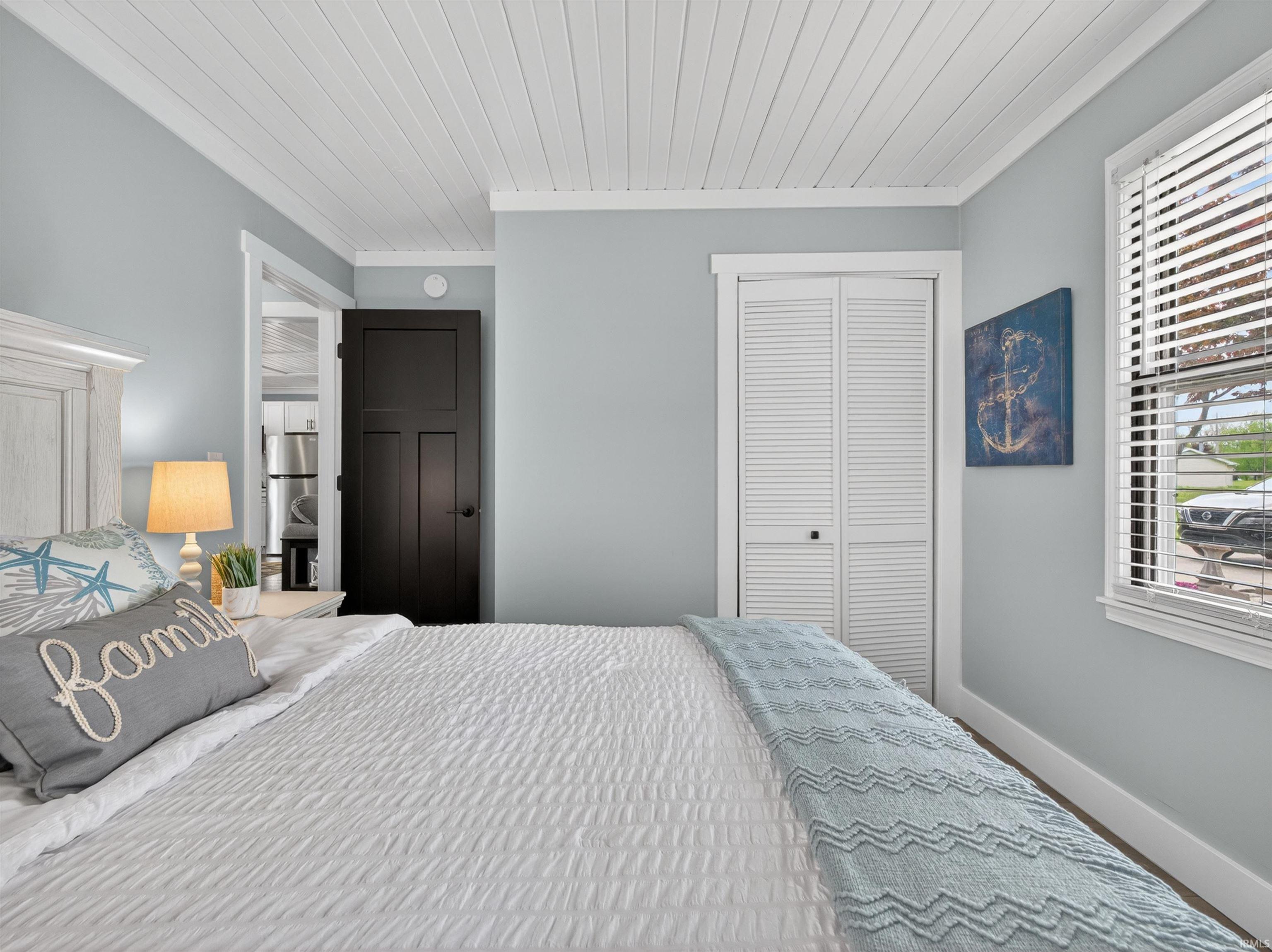 Bedroom featuring a white shiplap ceiling, light blue walls, and white trim