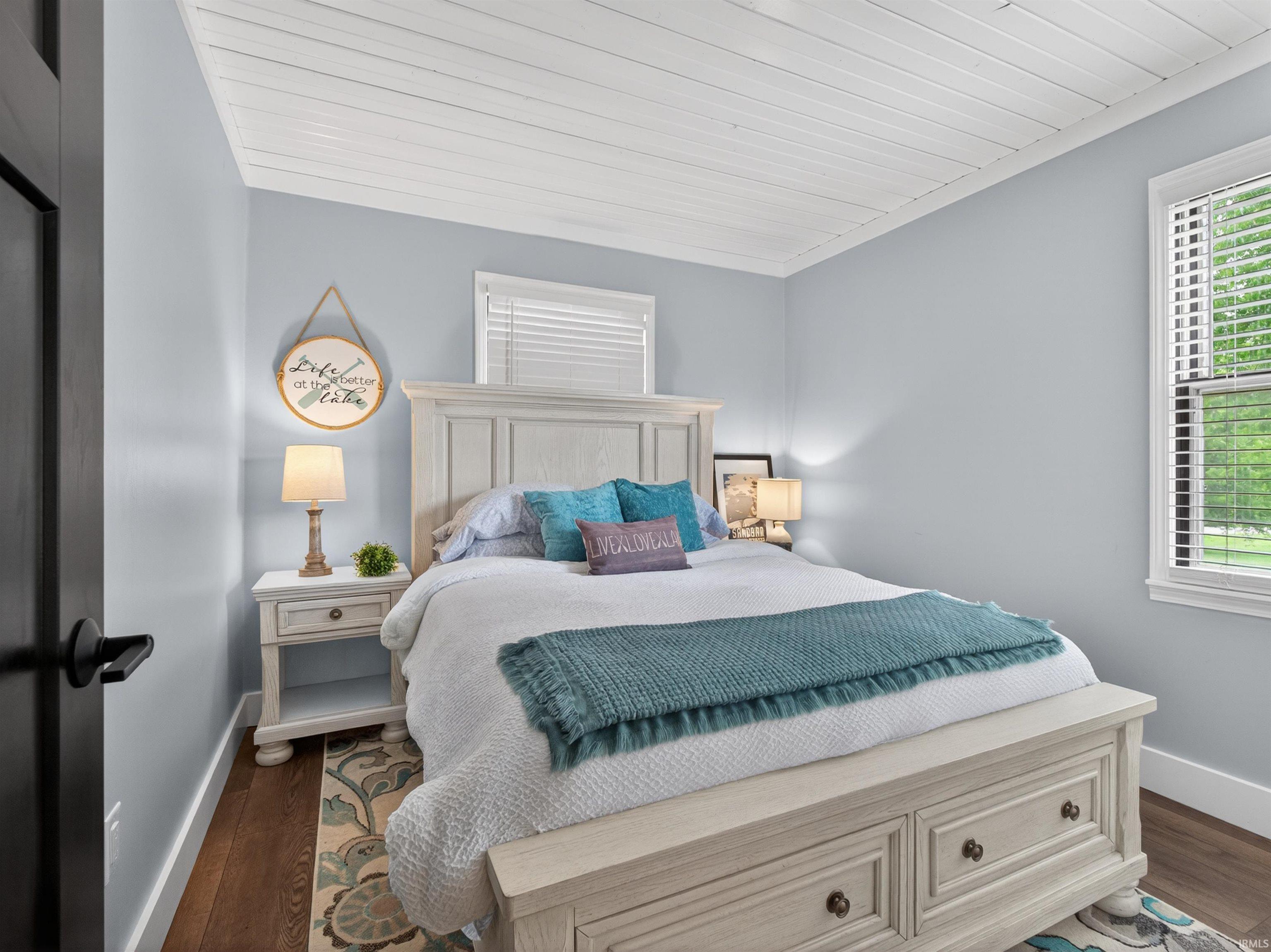 Bedroom featuring a white planked ceiling, light blue walls, and dark wood-finish flooring