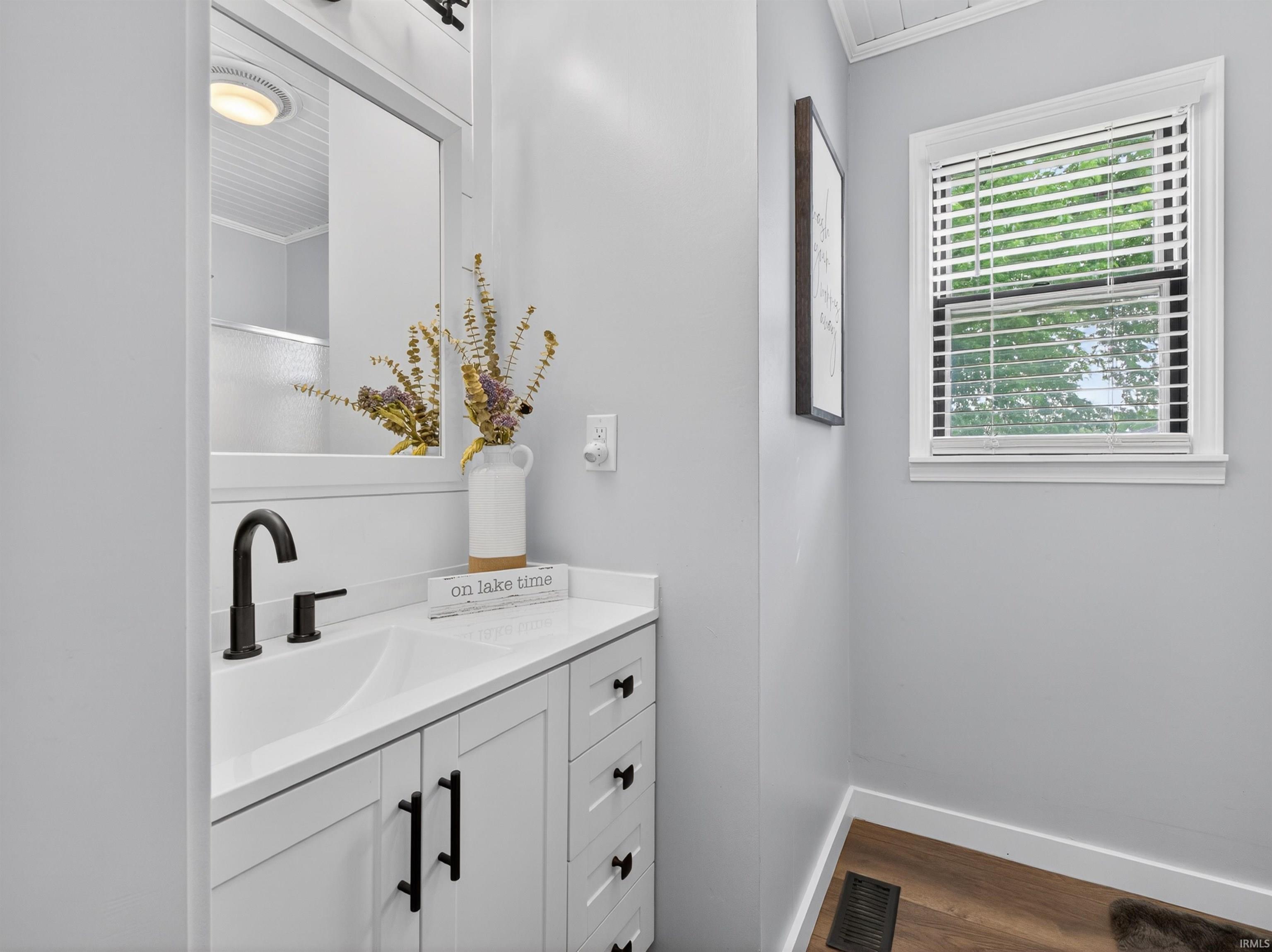 Bathroom vanity featuring a white countertop, undermount sink, and matte black faucet
