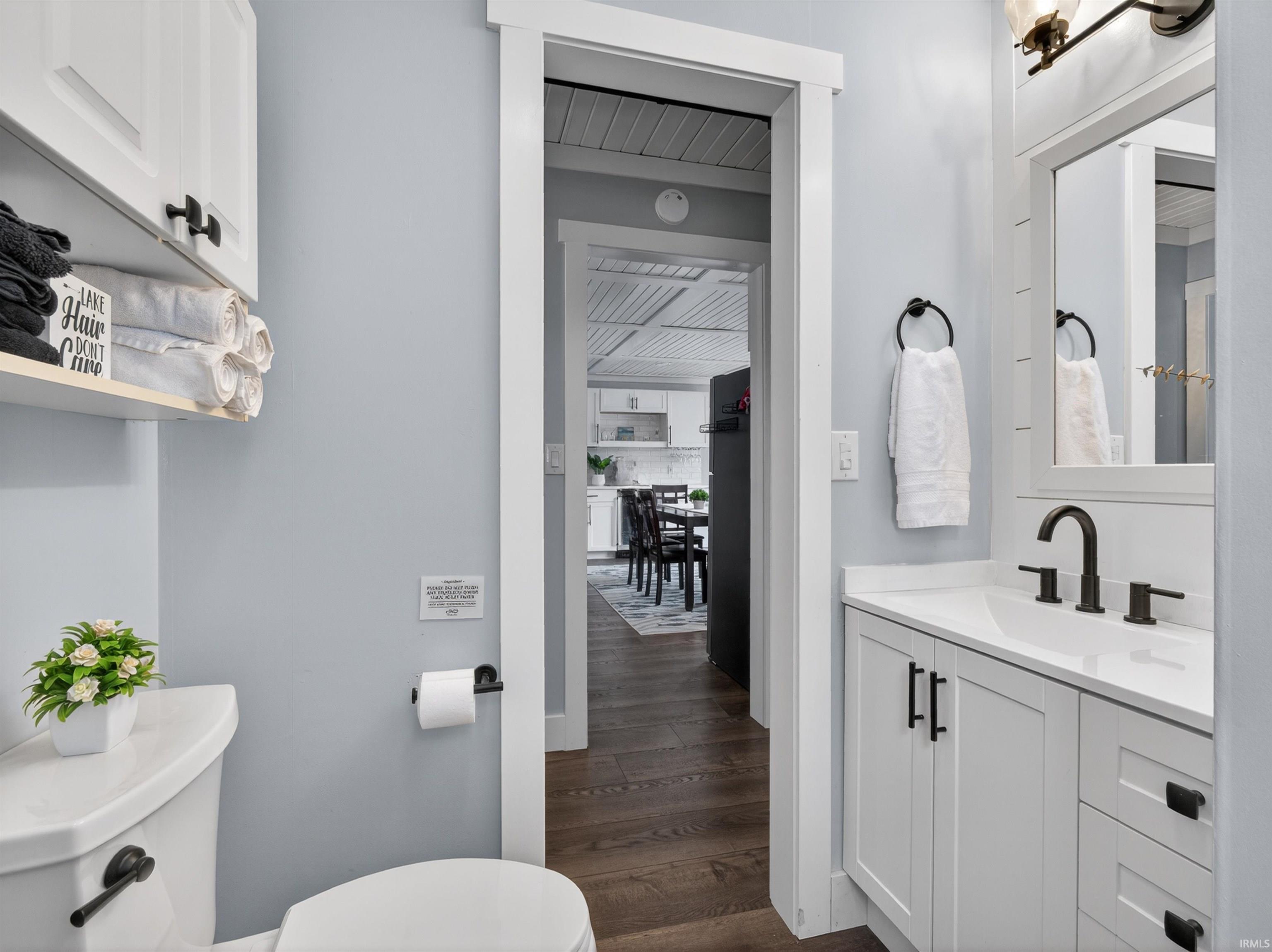 Bathroom vanity featuring white shaker-style cabinetry, a white countertop, and a black faucet