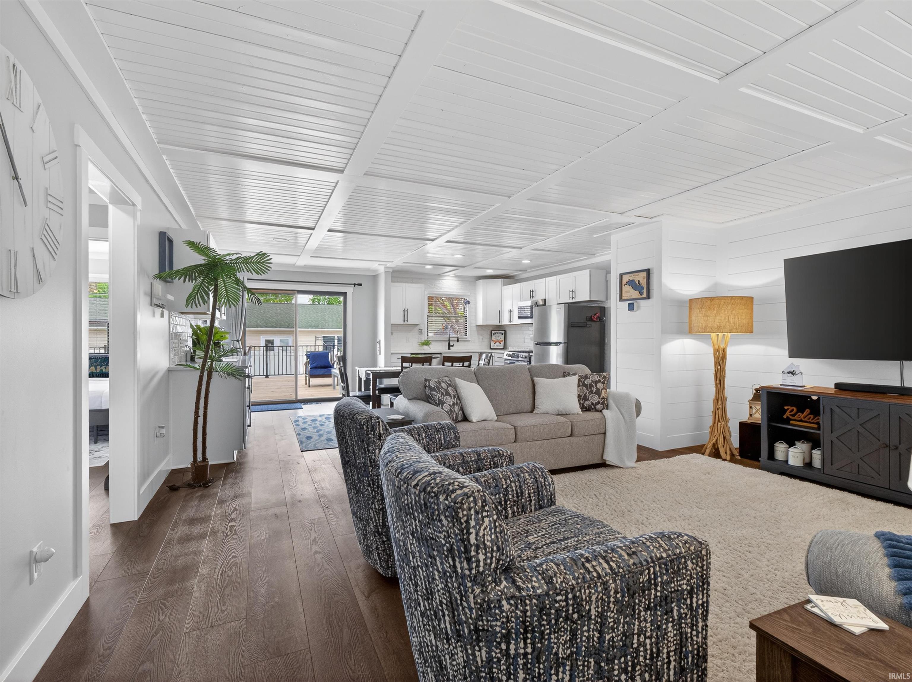 Open-concept living area featuring wood-finish flooring, a white shiplap wall, and a white planked ceiling