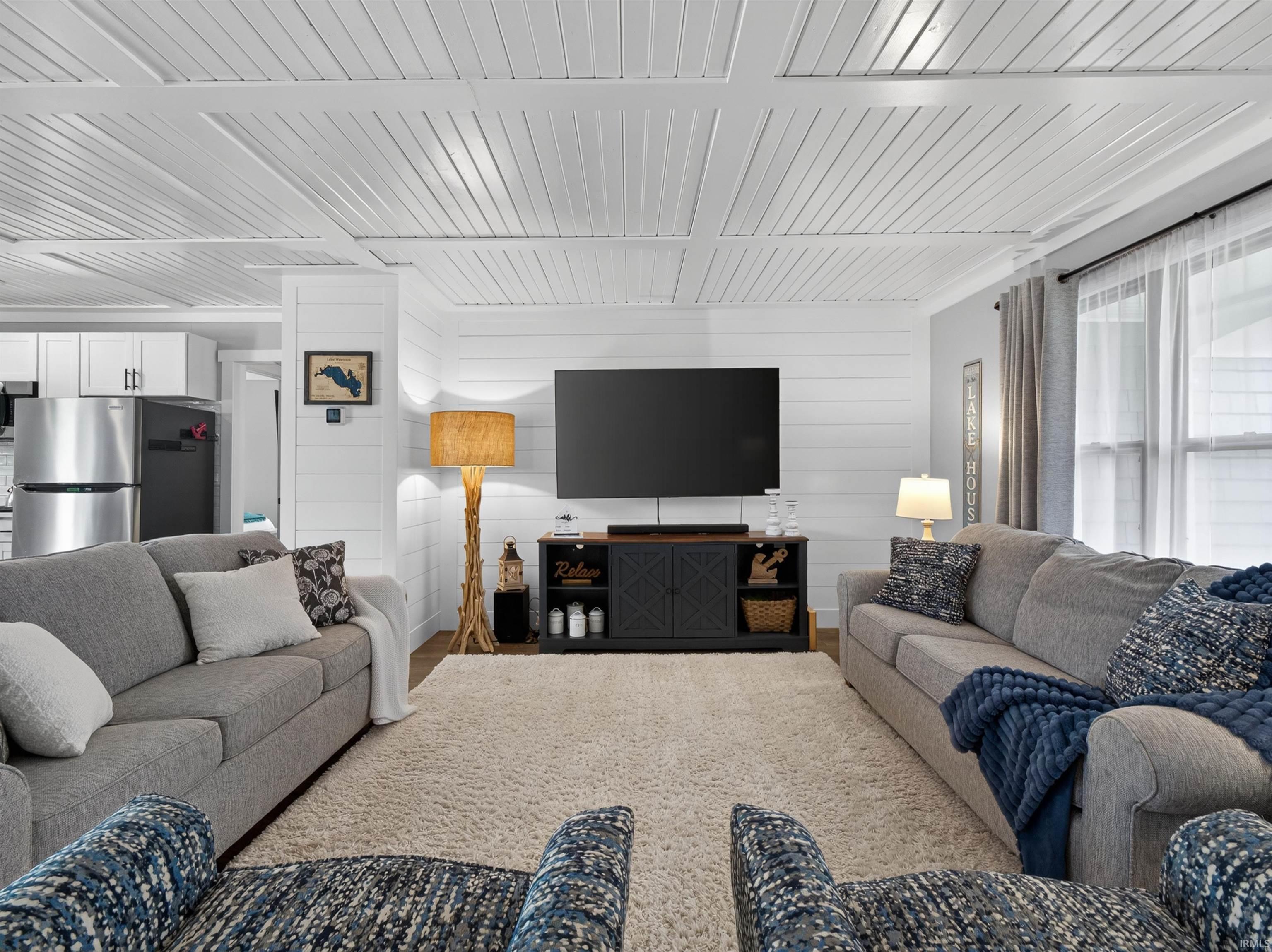 Open-concept living area featuring a coffered ceiling, shiplap accent wall, and wood-finish flooring