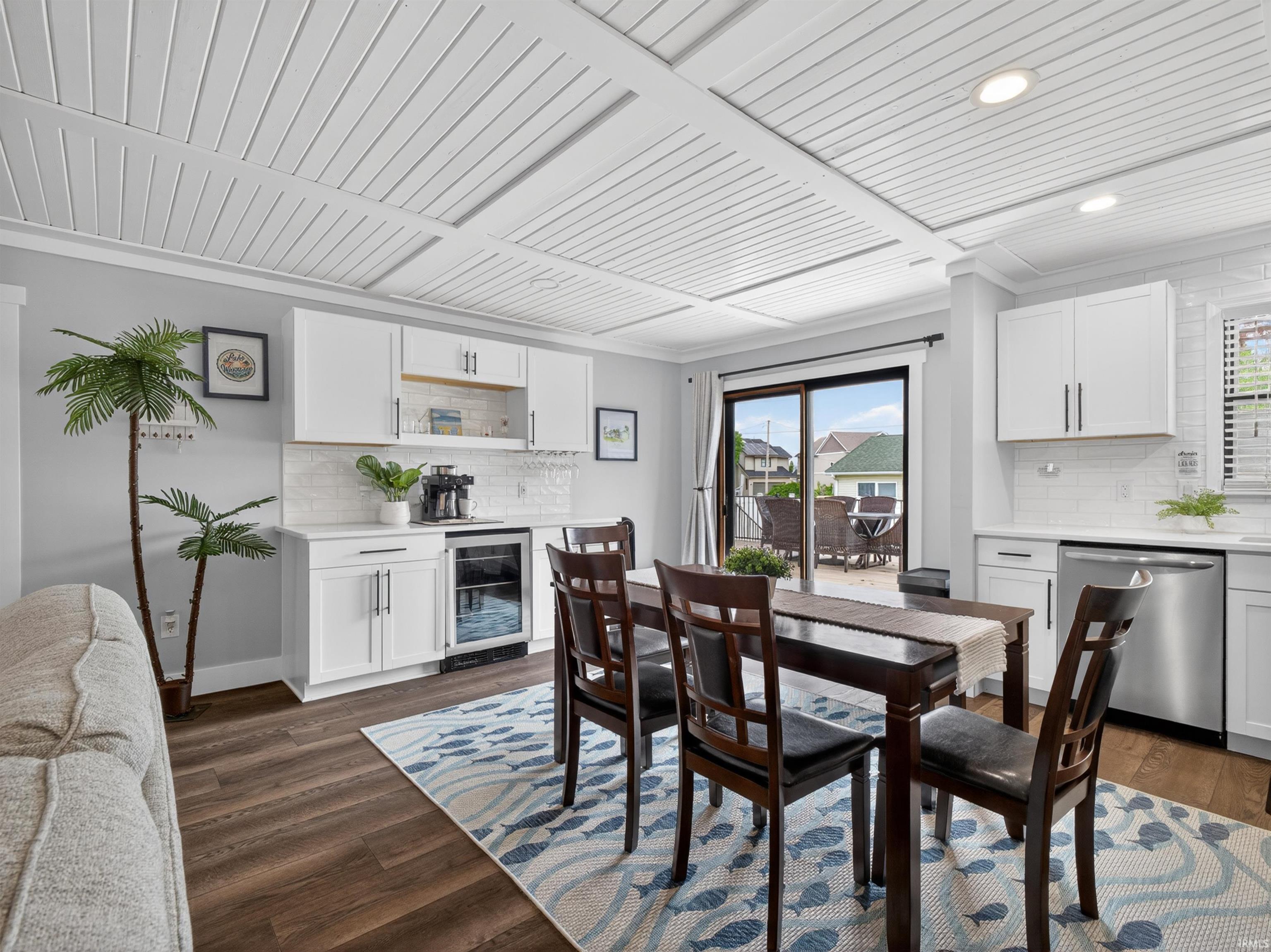 Dining area featuring white coffered ceilings, wood-finish flooring, and a glass slider to an outdoor space